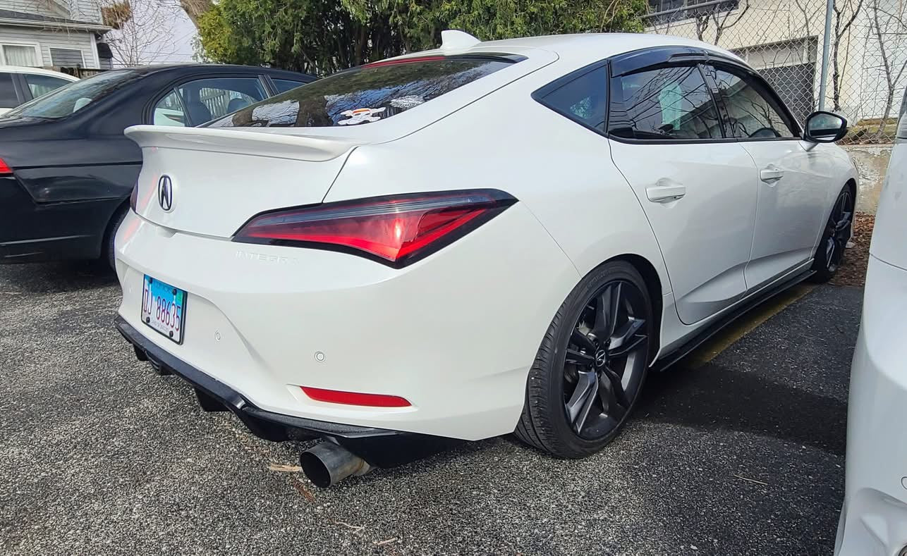 Angled side-rear view of a white Acura Integra with the rear trunk lip