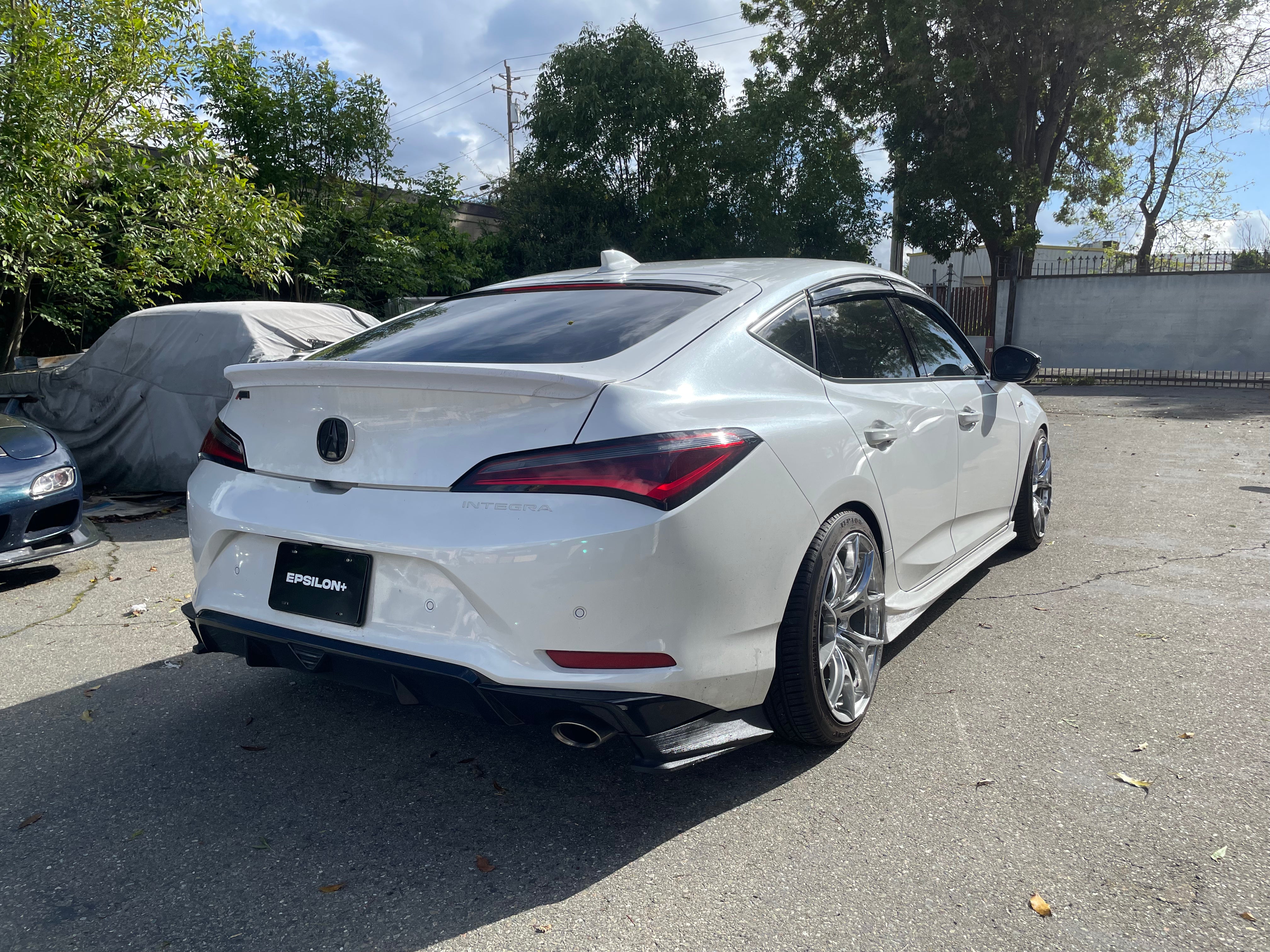 White Acura Integra with the Epsilon+ rear trunk lip parked outdoors