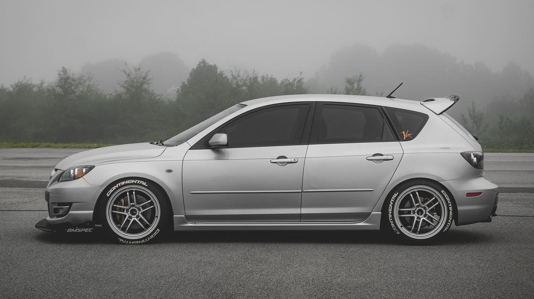 Front three-quarter view of a silver Mazdaspeed3 Gen1 with front splitter in fog