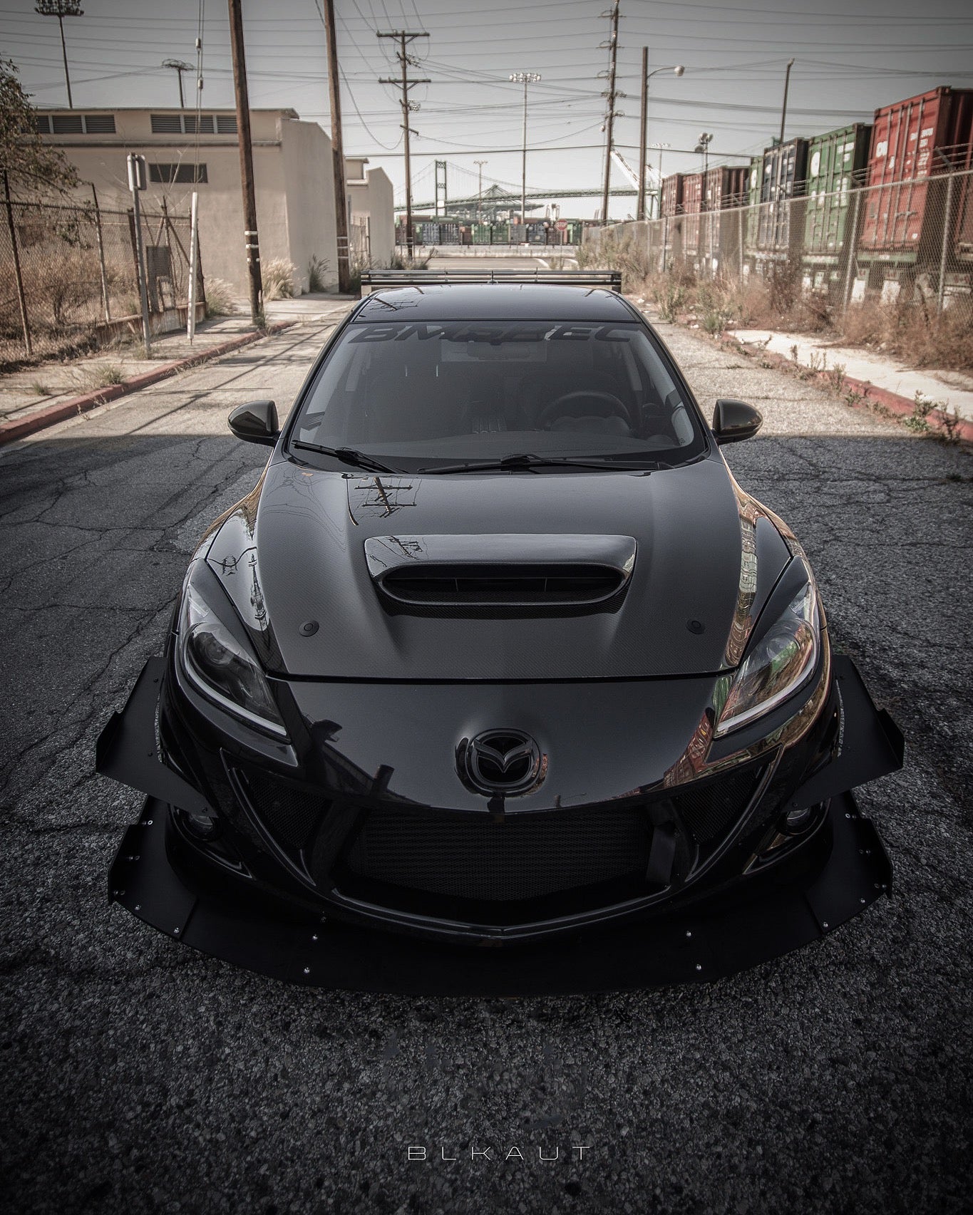 Front-on view of a black Mazdaspeed3 Gen2 with wide front splitter and canards