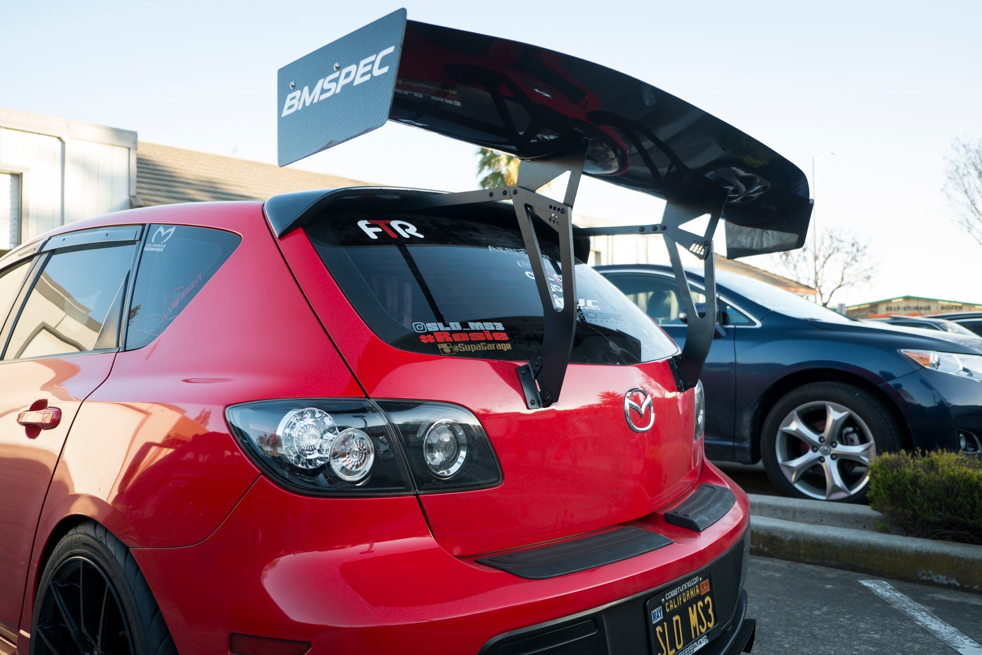 Close-up of the GT wing mounted on a red Mazdaspeed3 Gen1 roofline
