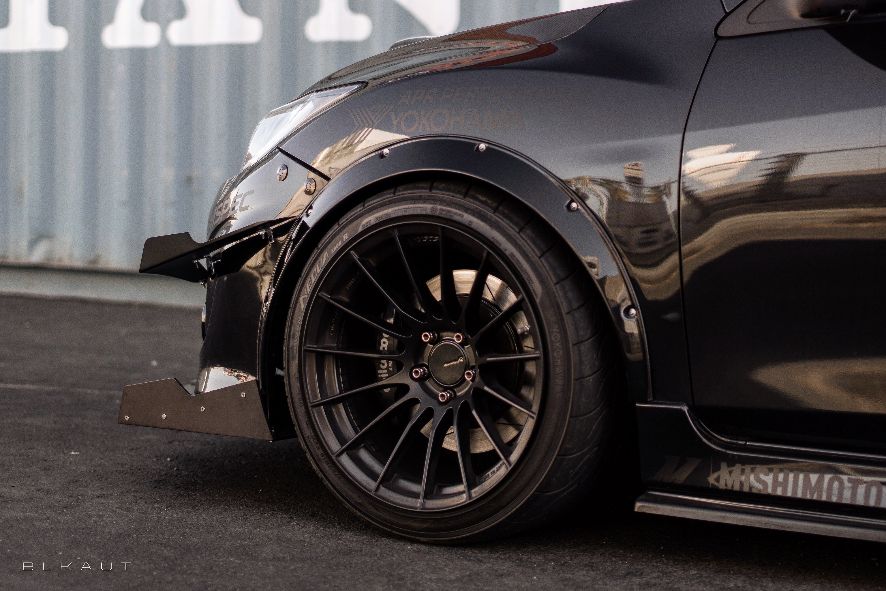 Close-up of the front splitter on a black Mazdaspeed3 Gen2 fender and wheel