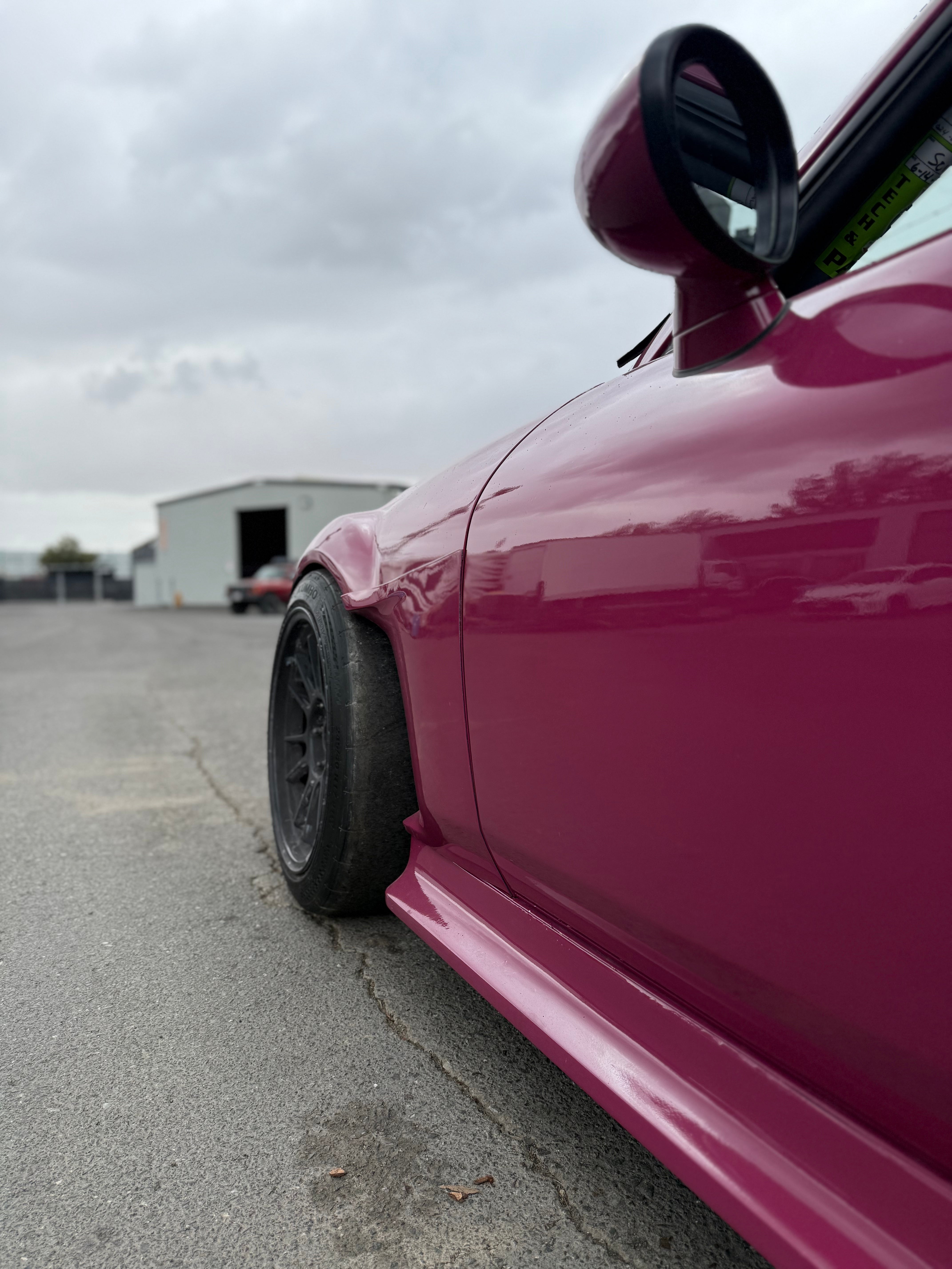 Side-rear view of a pink Mazda MX-5 Miata NC showing the fender cut profile