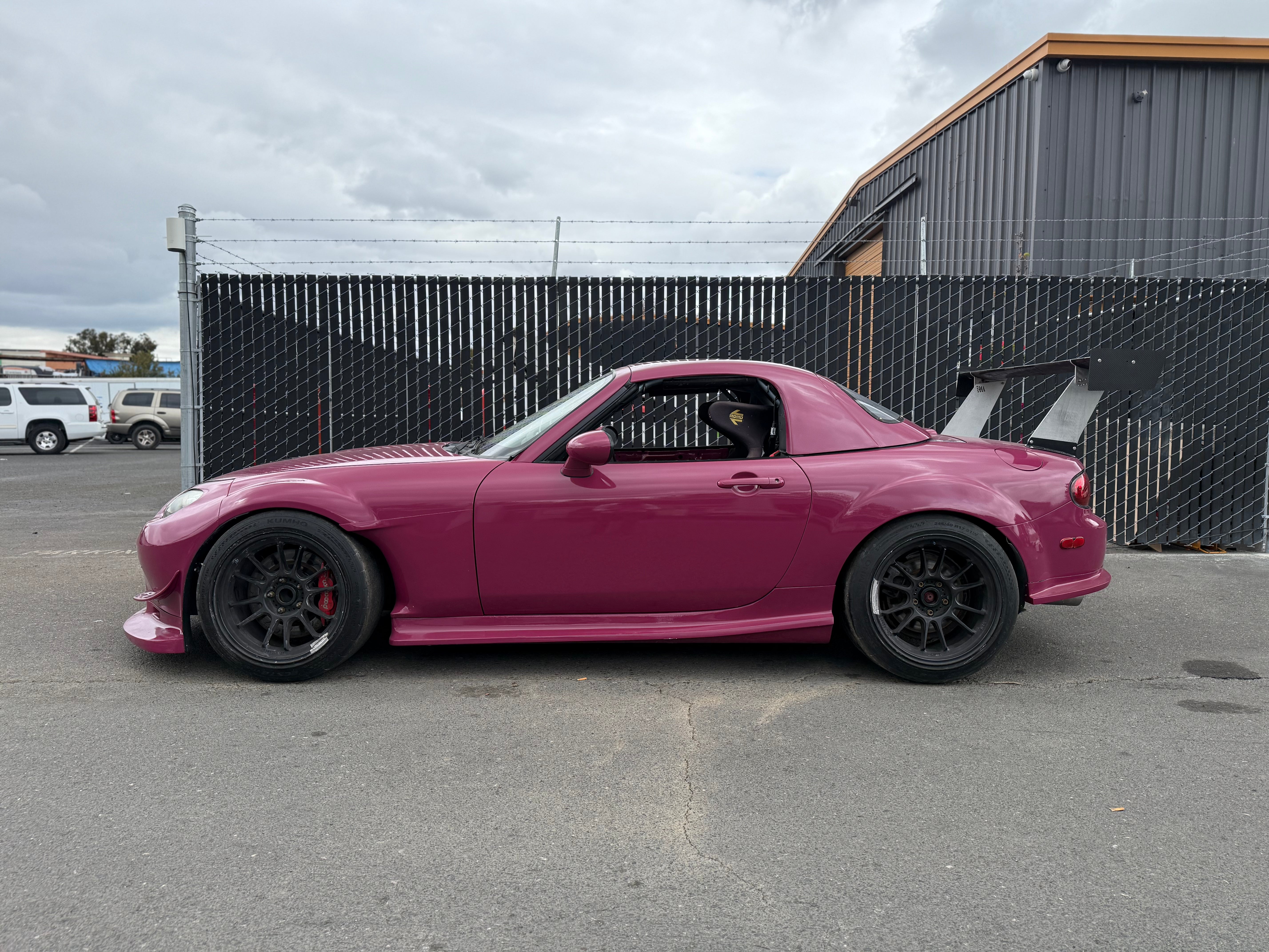 Side profile of a pink Mazda MX-5 Miata NC with Epsilon+ side skirts and hardtop