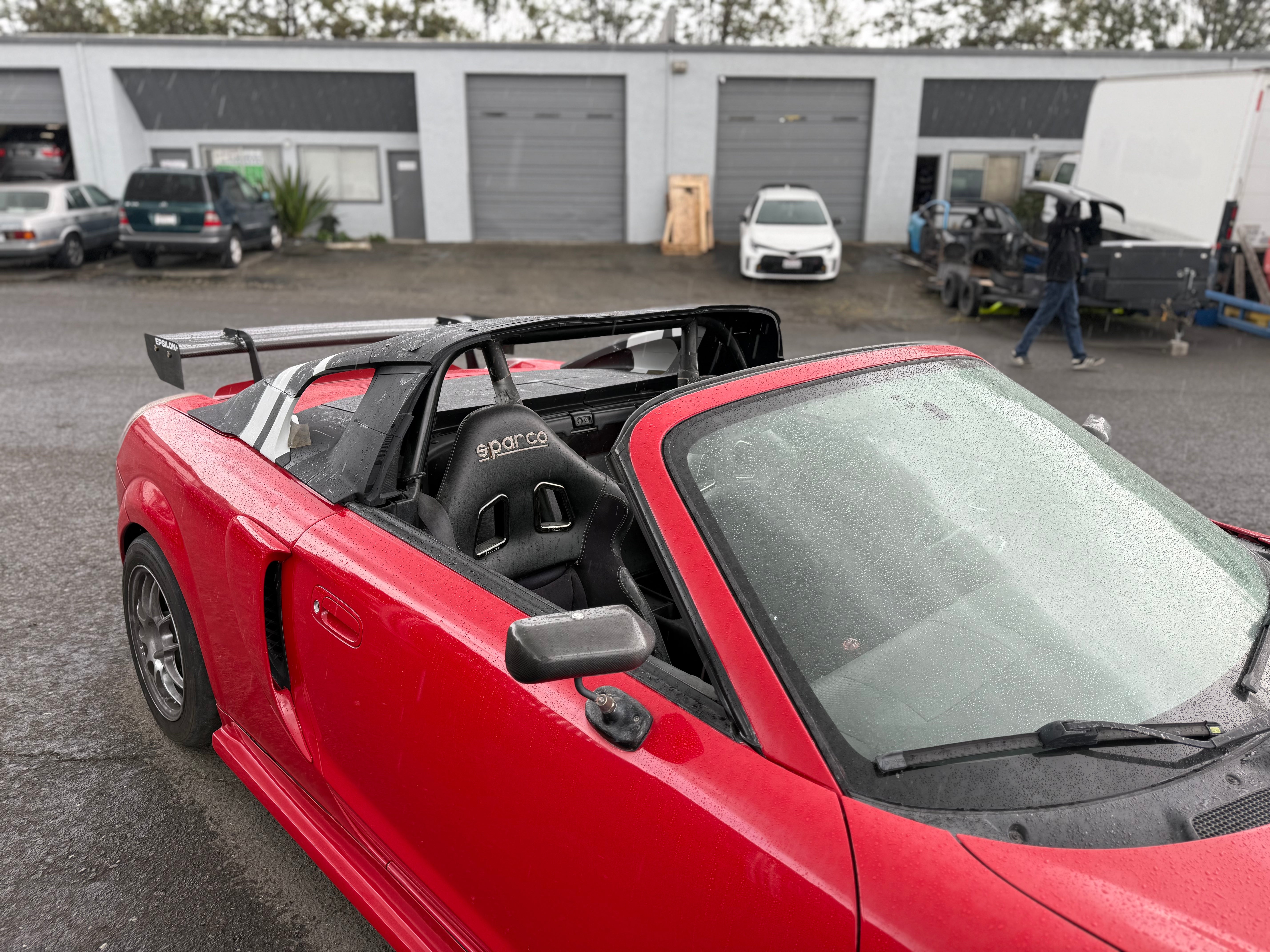 Cabin and roll bar view of a red MR2 Spyder with the hardtop removed