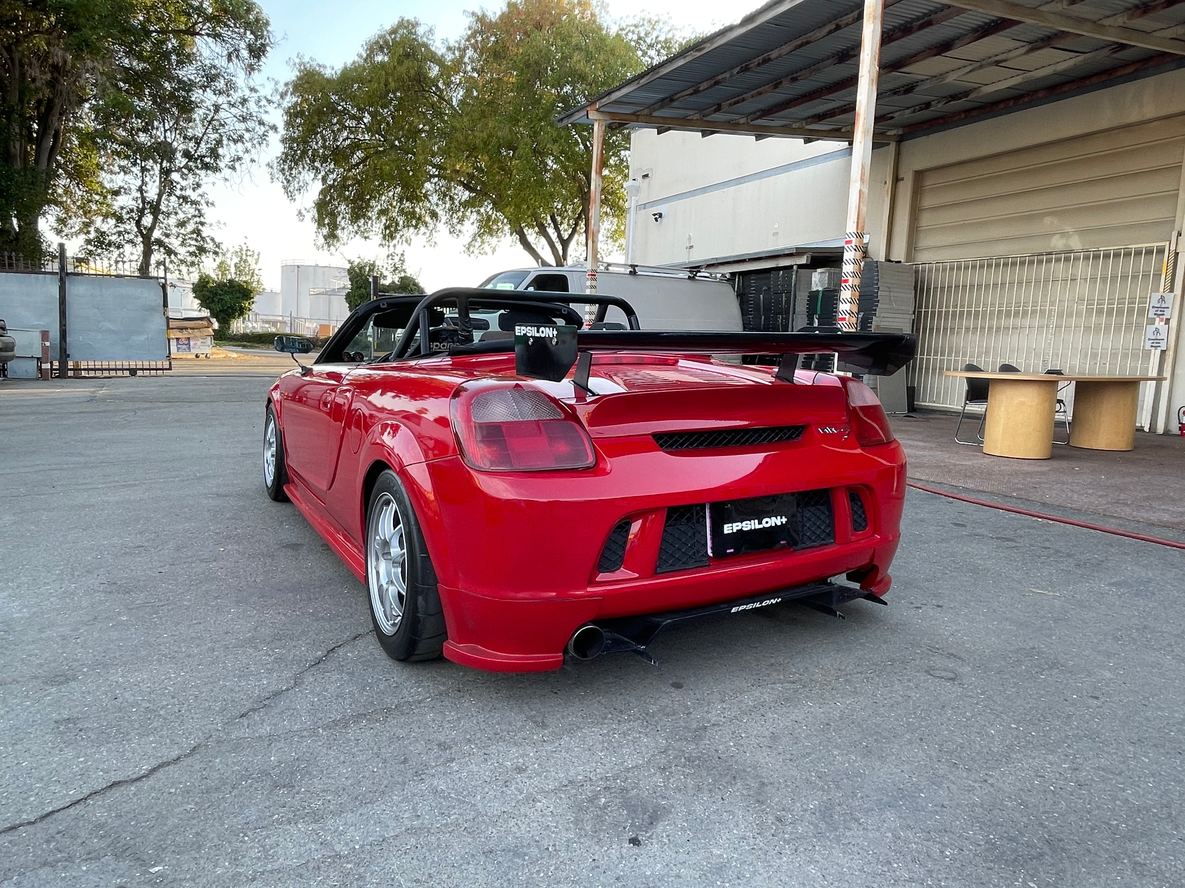 Rear three-quarter view of a red MR2 Spyder with rear bumper spats fitted