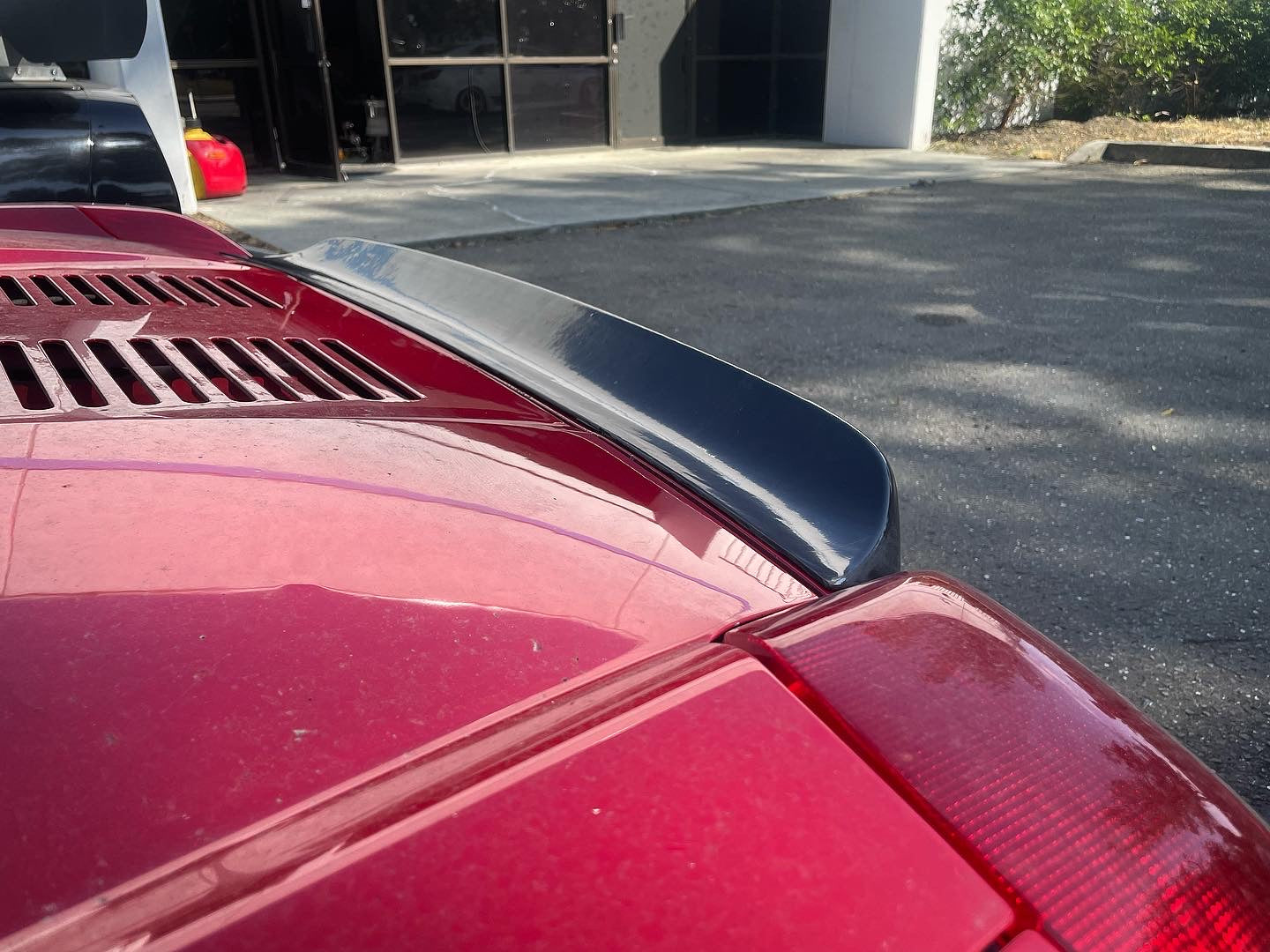 Angled view of the duckbill spoiler above the engine deck vents on a red MR2 Spyder