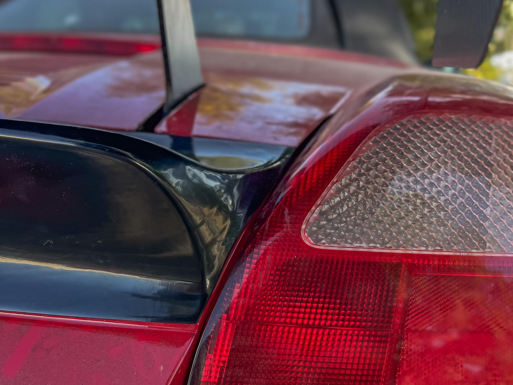 Close-up of the duckbill spoiler edge beside the taillight on a red MR2 Spyder