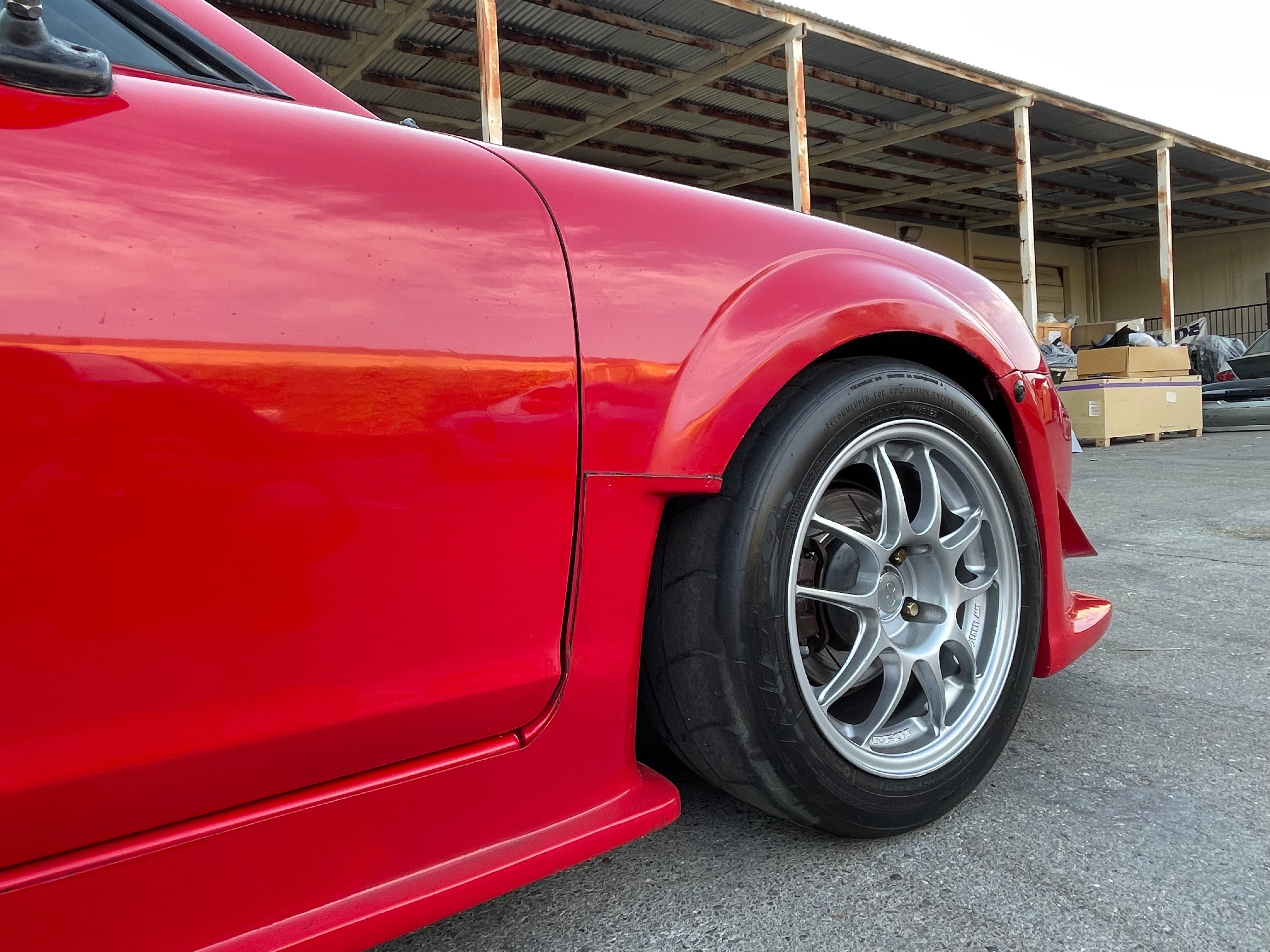 Close-up of the rear fender extension and side skirt on a red MR2 Spyder