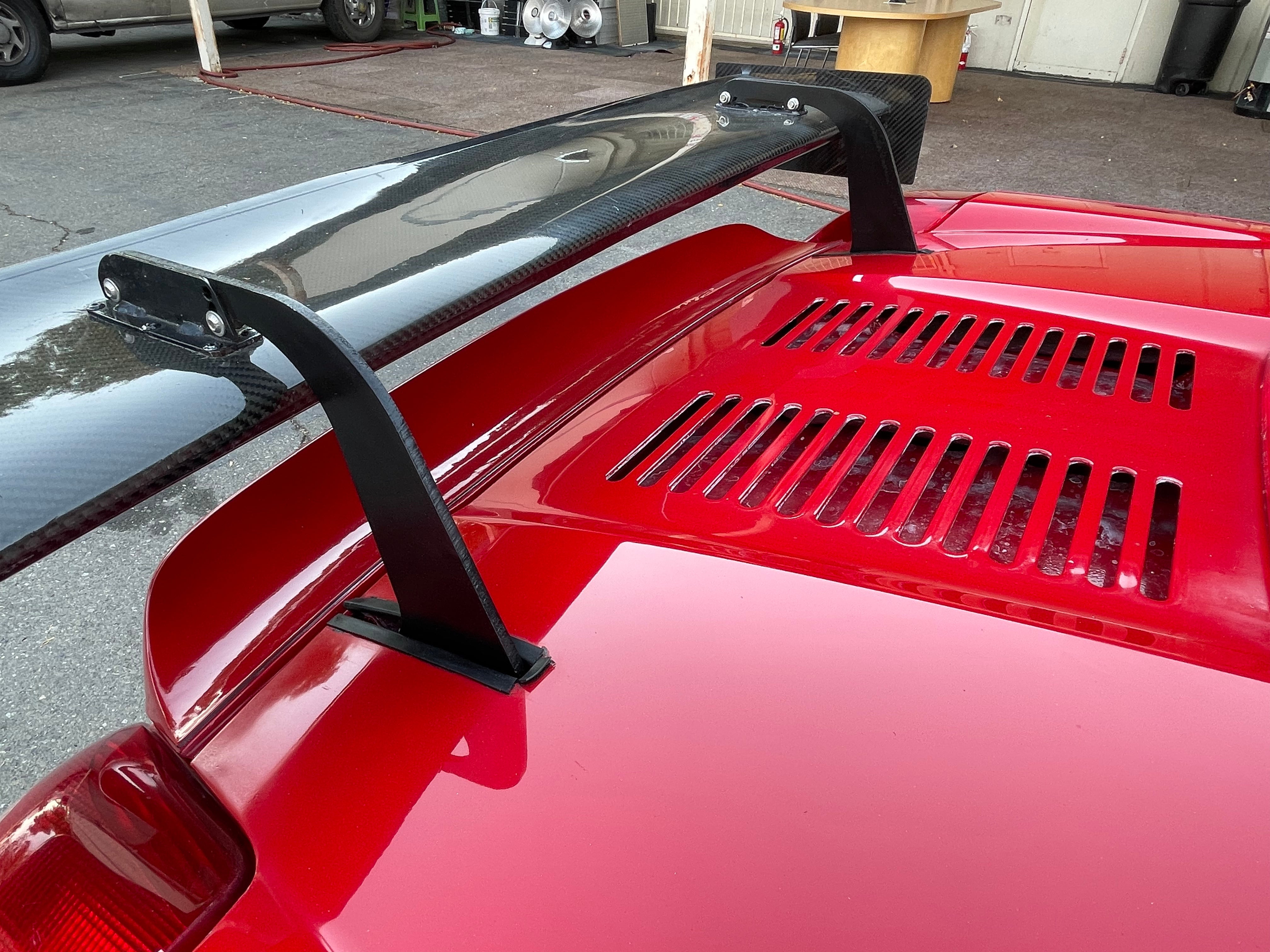 Close-up of the rear wing mount on the engine deck of a red MR2 Spyder