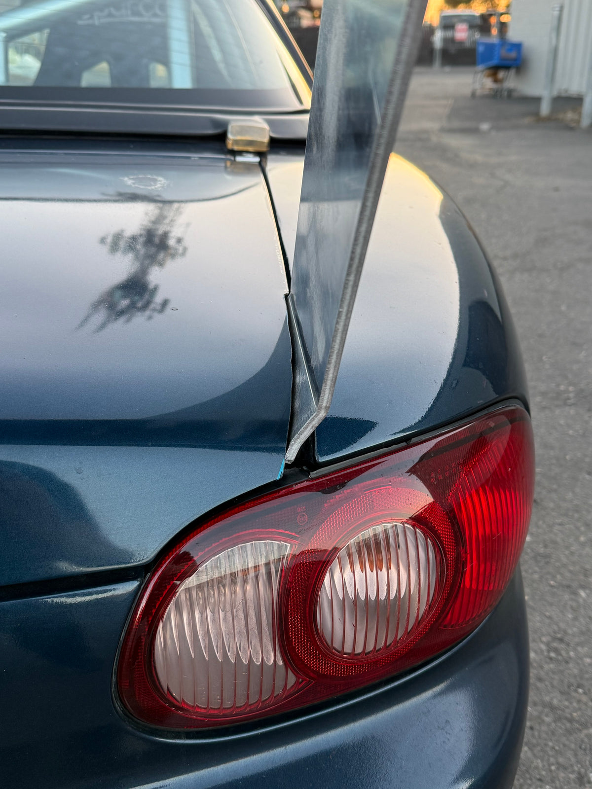 Close-up of the TC Wing upright passing the NB Miata tail light and deck lid edge