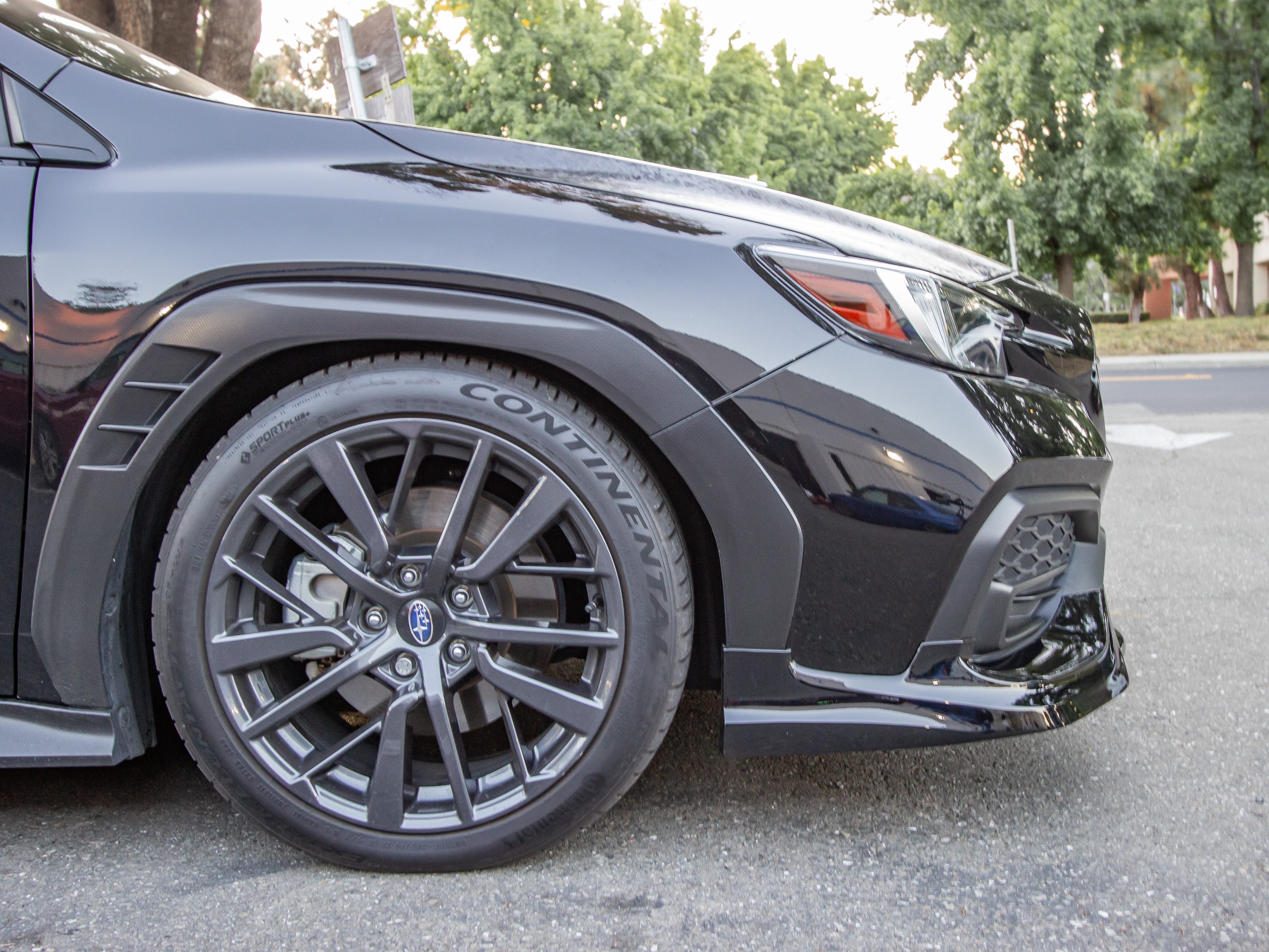 Front three-quarter view of a black Subaru WRX VB with front lip and gray wheels