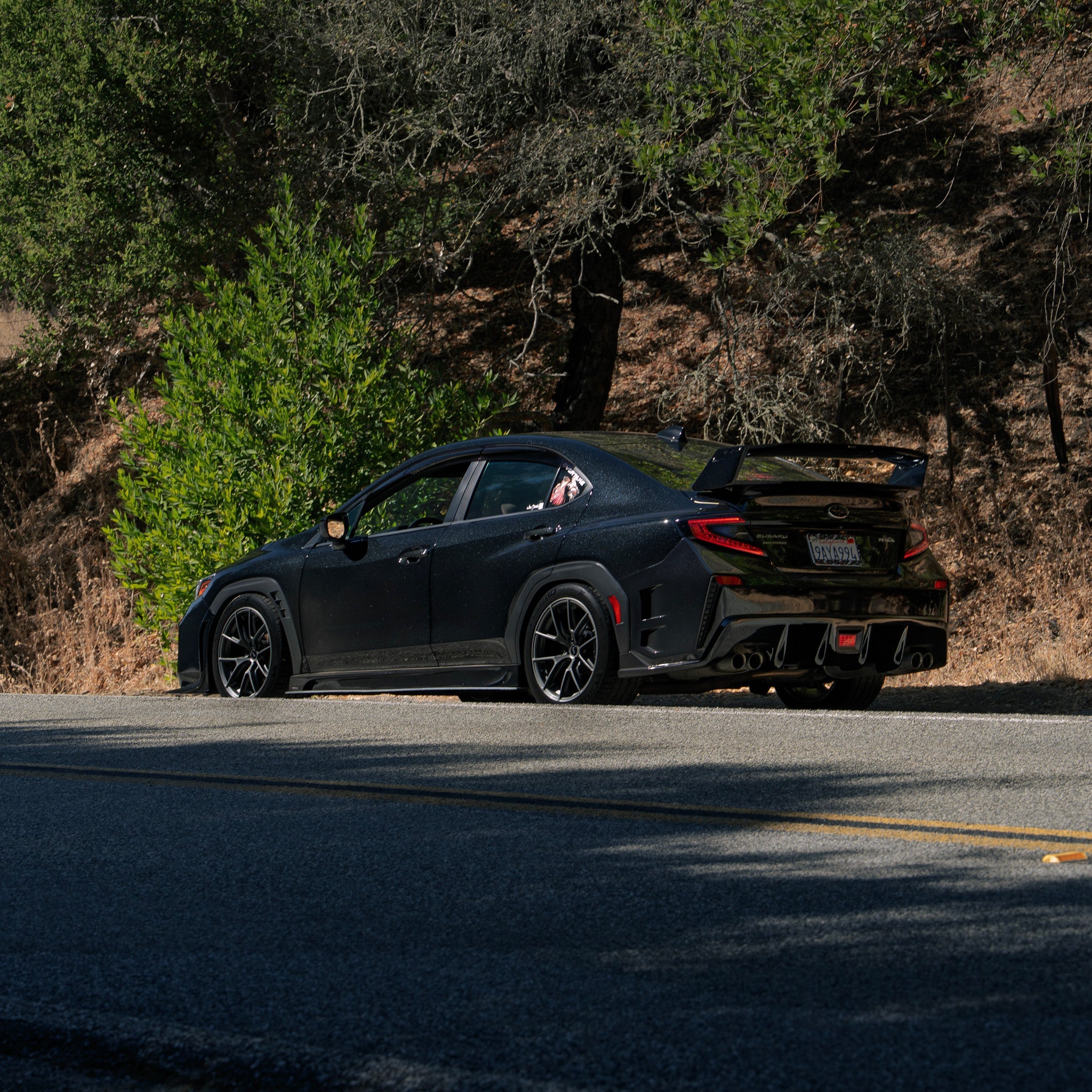 Rear three-quarter view of a black Subaru WRX VB with prototype rear bumper parked on a road