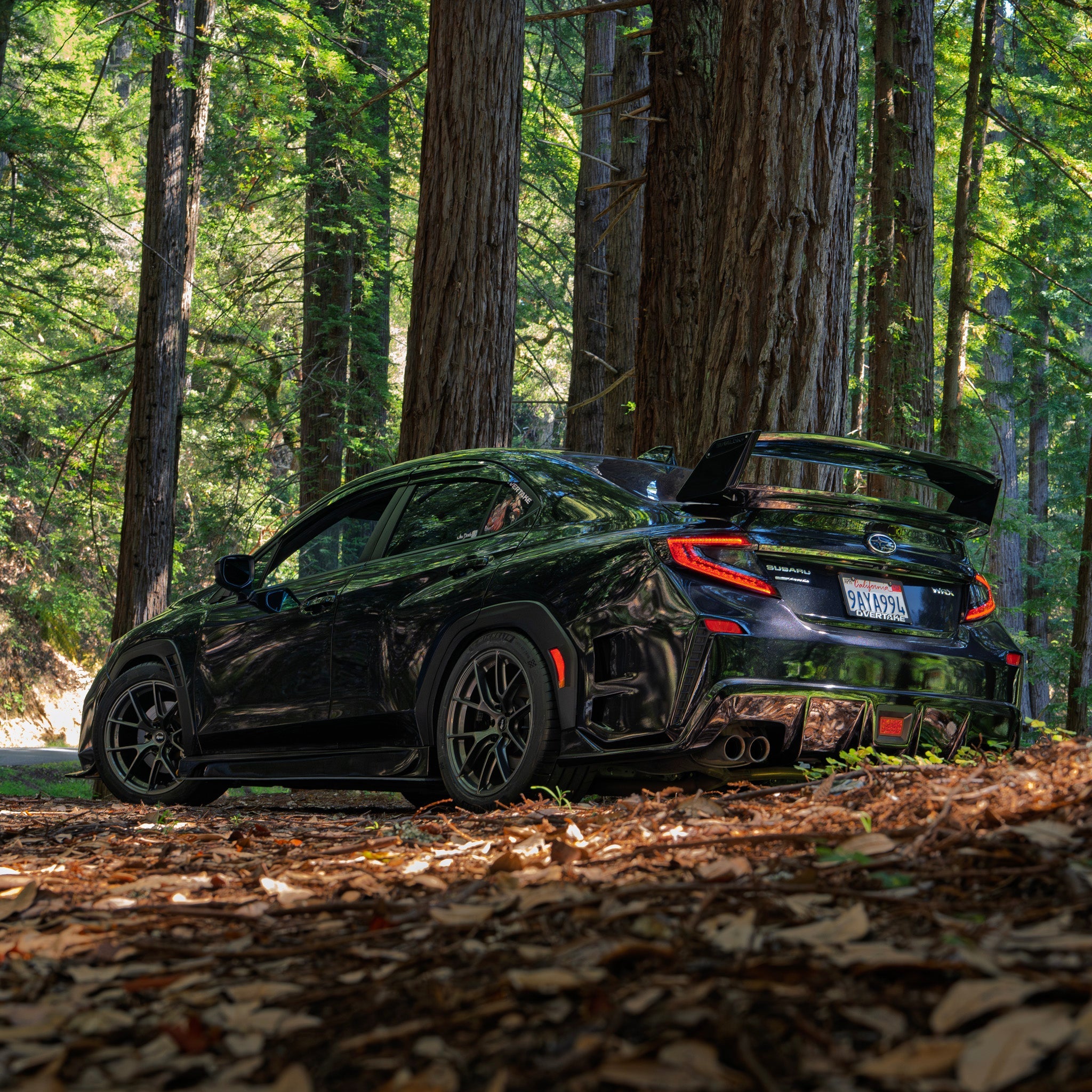 Rear three-quarter view of a black Subaru WRX VB with prototype rear bumper among fallen leaves