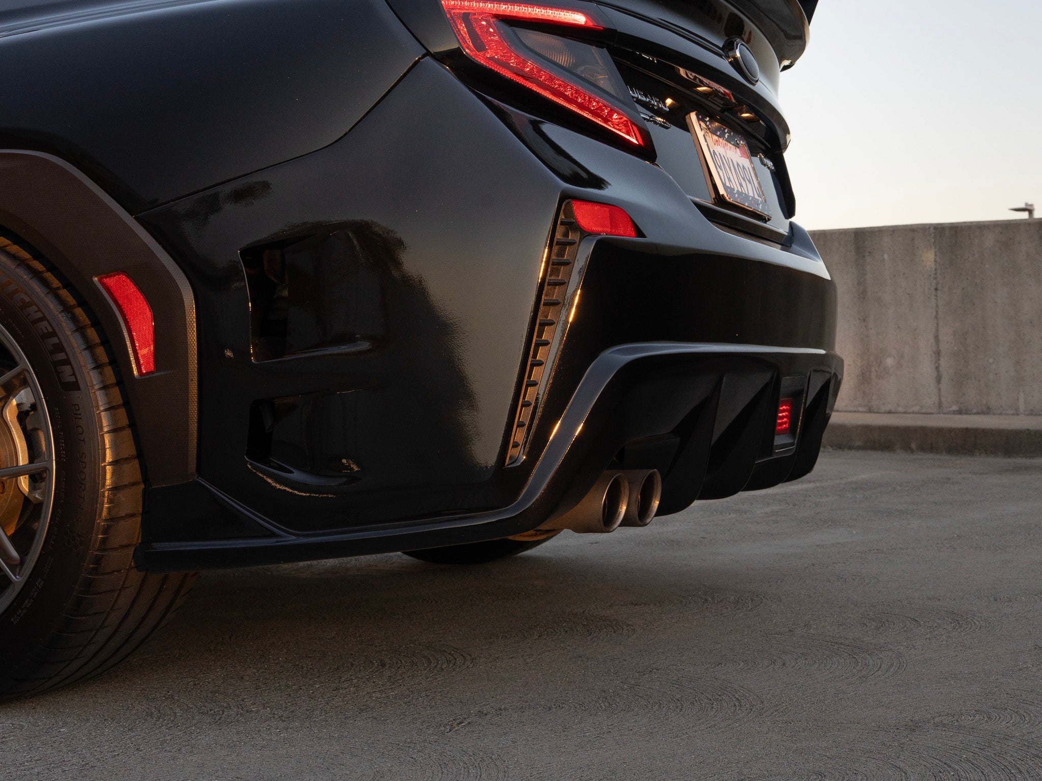 Close-up of the rear bumper corner on a black Subaru WRX VB in a parking structure