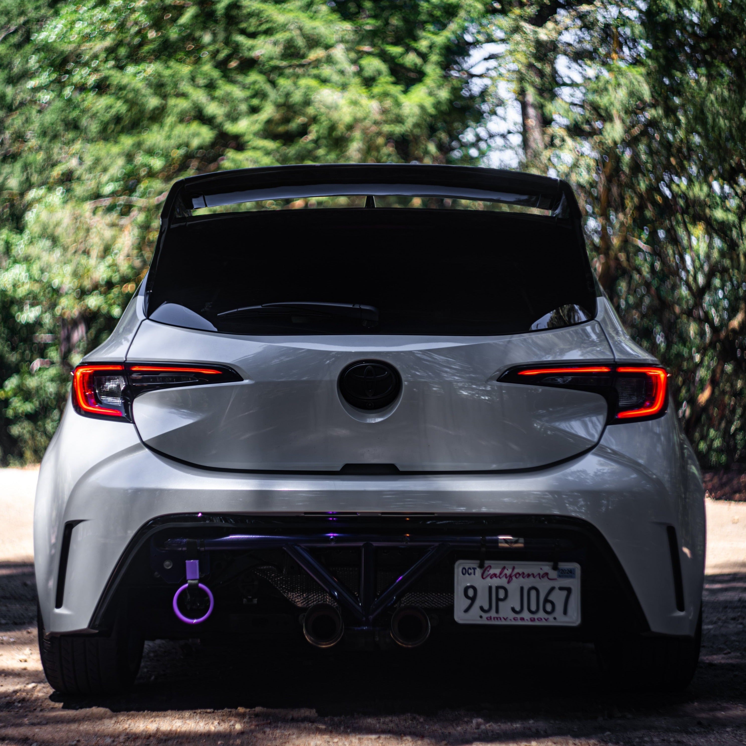 Side profile of a white Corolla Hatchback with WRC Wing V3 on a track