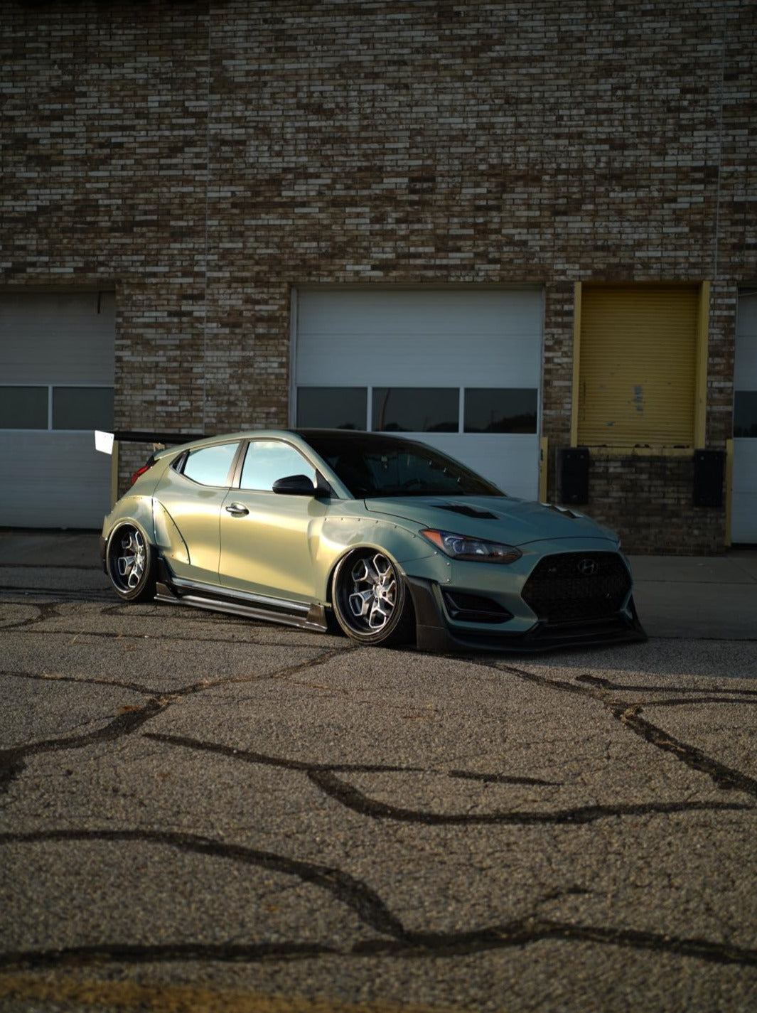 Side profile of a Hyundai Veloster JS with GT wing parked outside a garage