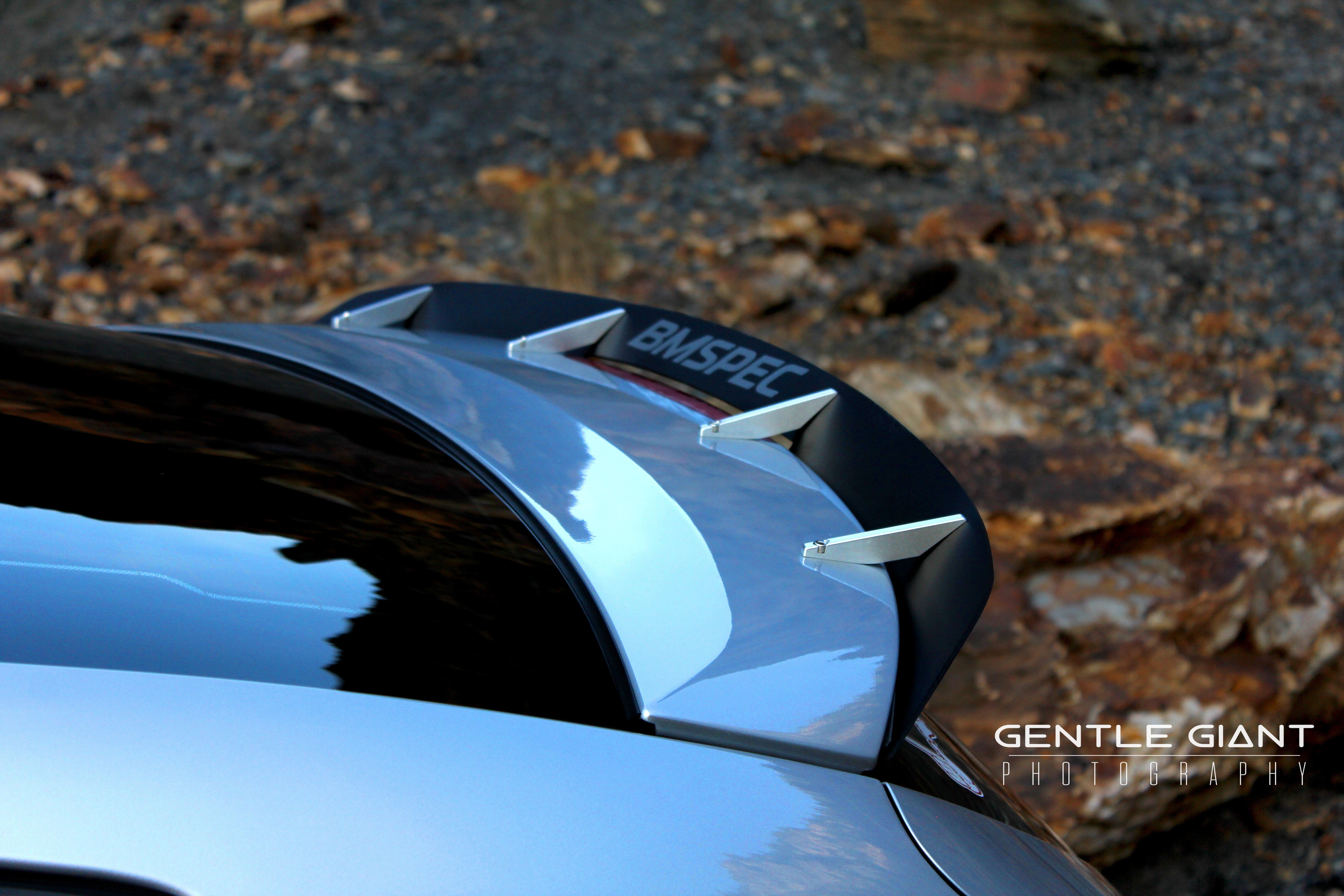 Spoiler extension mounted on a white Veloster Turbo parked on a mountain road