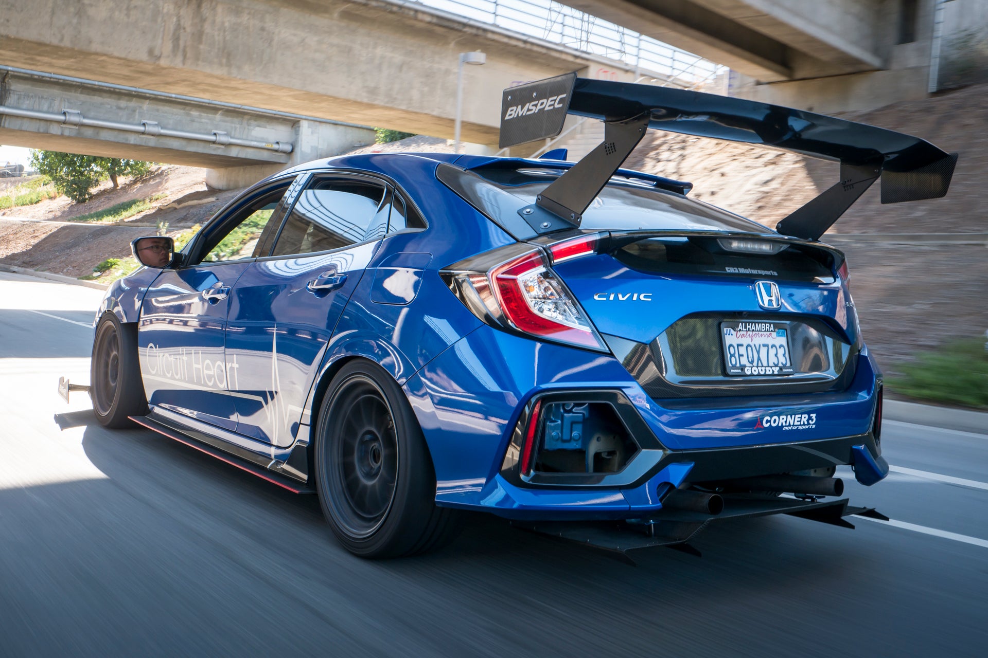 Blue Honda Civic Hatchback FK7 with V1C+ diffuser and GT wing, rolling shot on the highway
