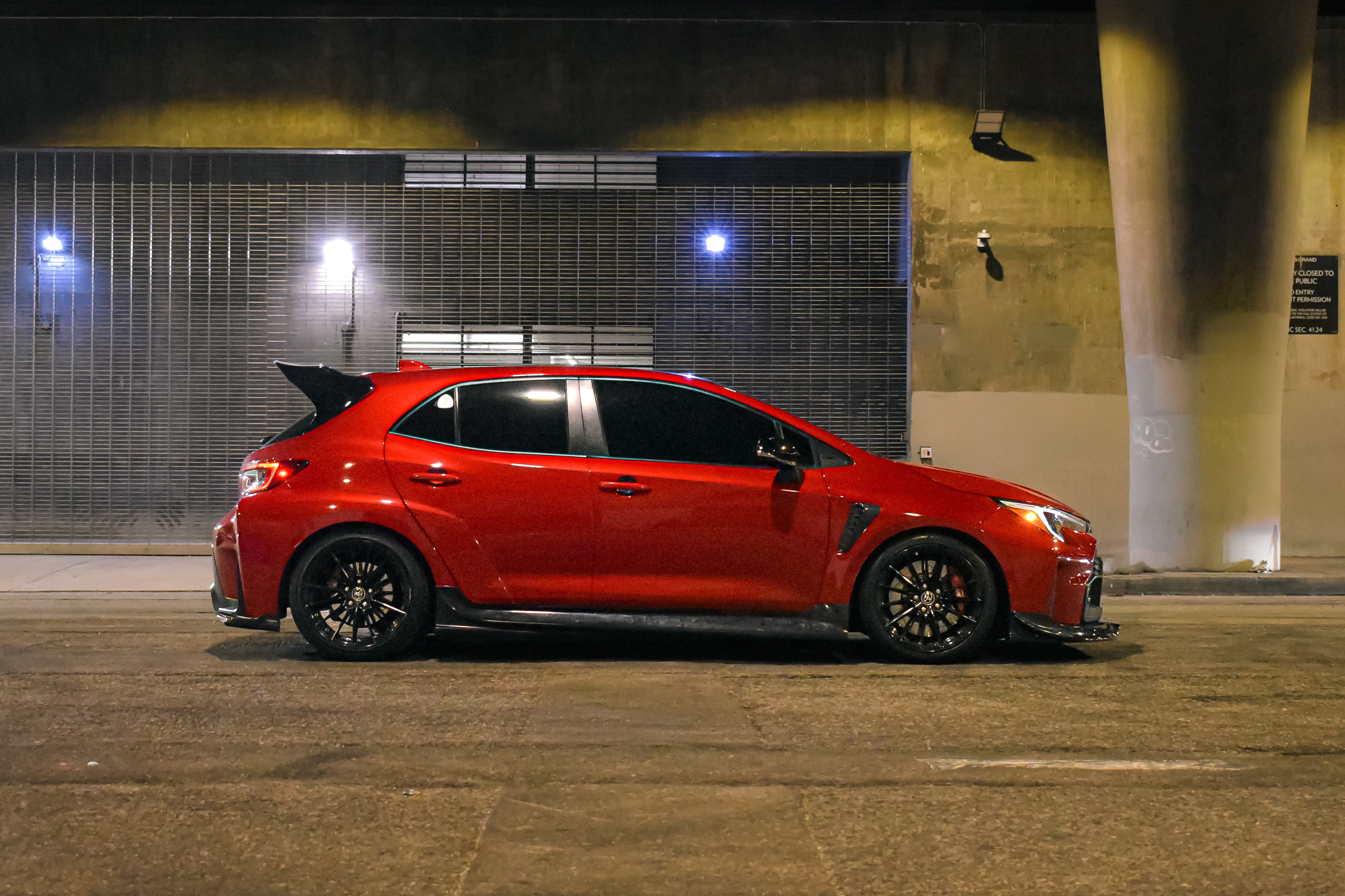 Side profile of a red GR Corolla with side skirts V2 in a parking garage at night