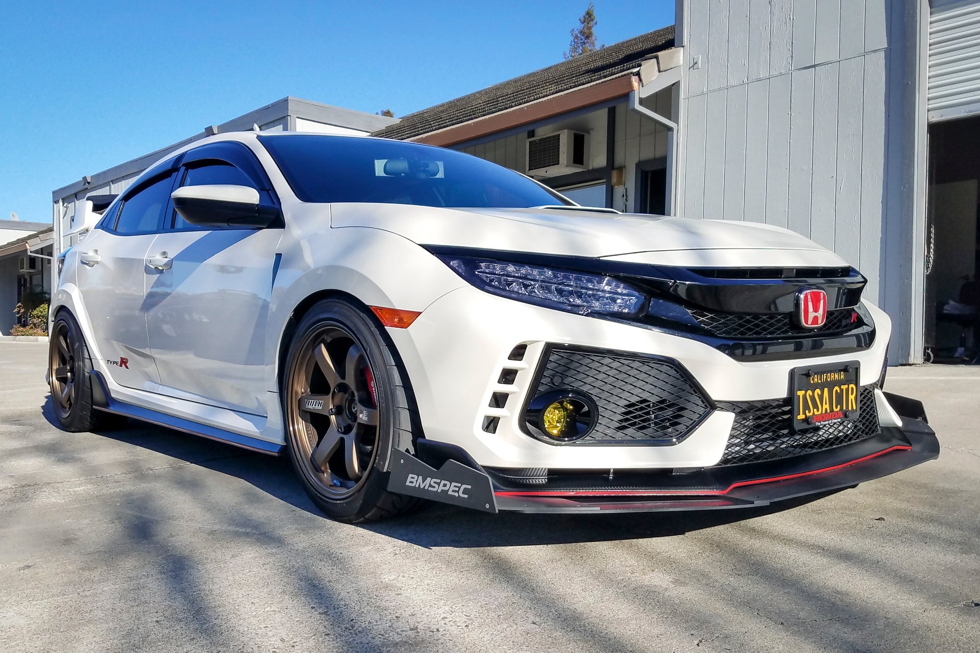 Front three-quarter view of a white Civic Type R FK8 with front splitter and bronze wheels
