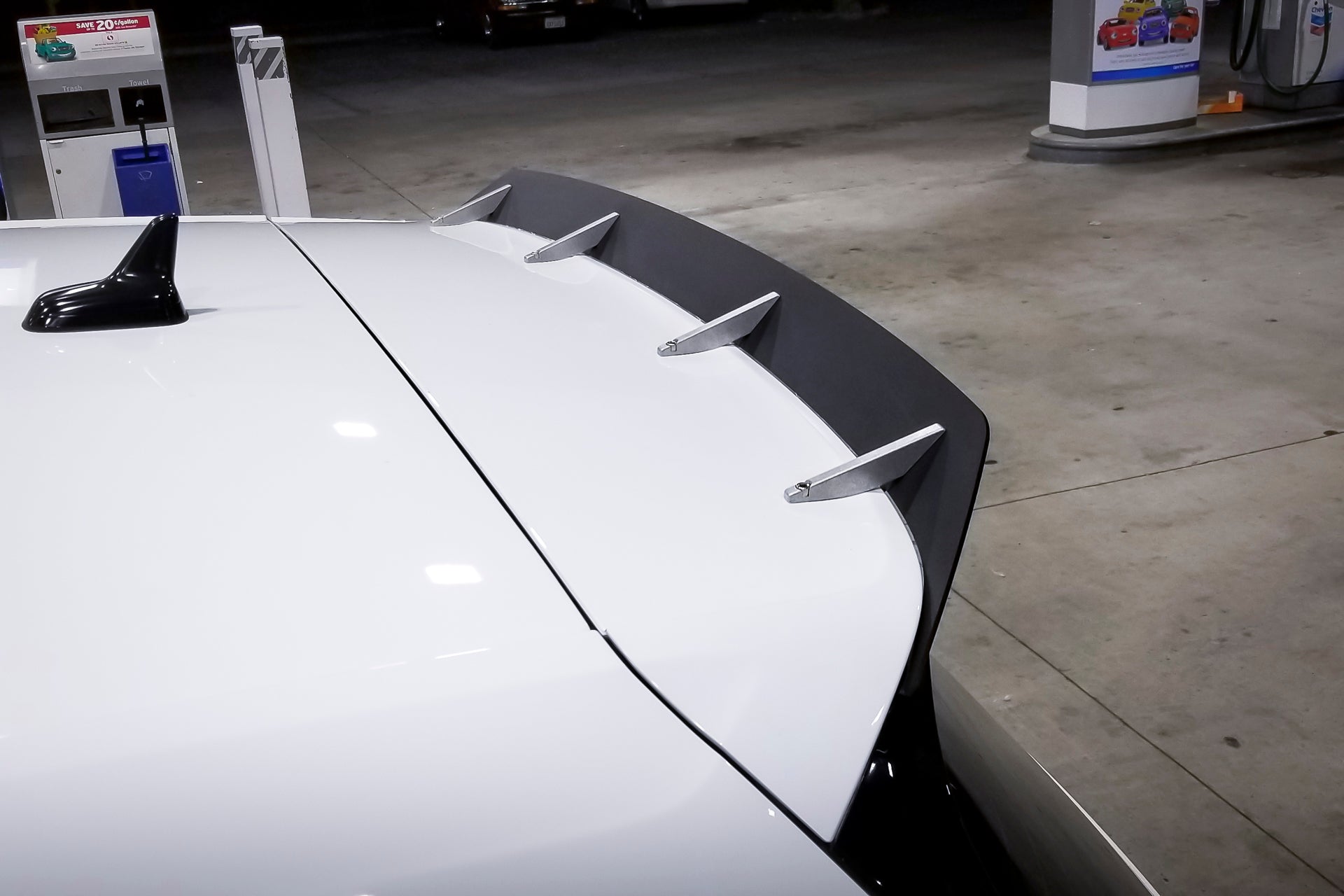 Close-up of the spoiler extension mounted on a white Golf R roofline at night