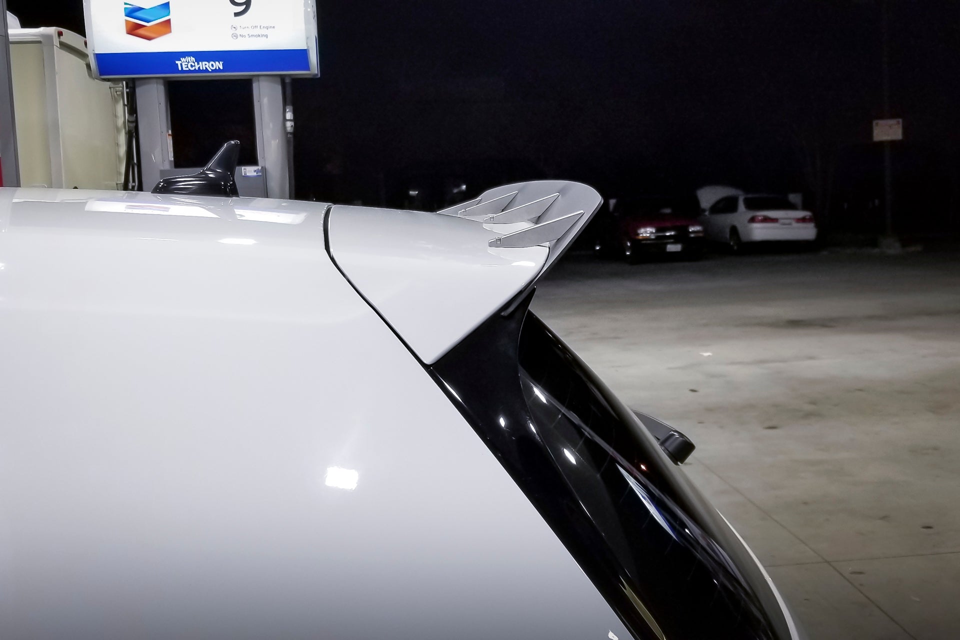 Side view of the spoiler extension on a white Golf R at a gas station