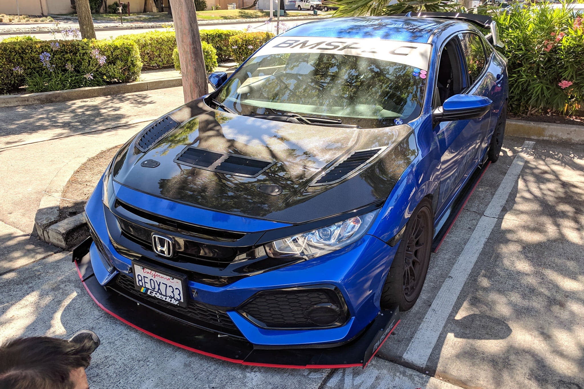 Front three-quarter view of a blue Civic Hatchback Sport with front splitter and carbon hood