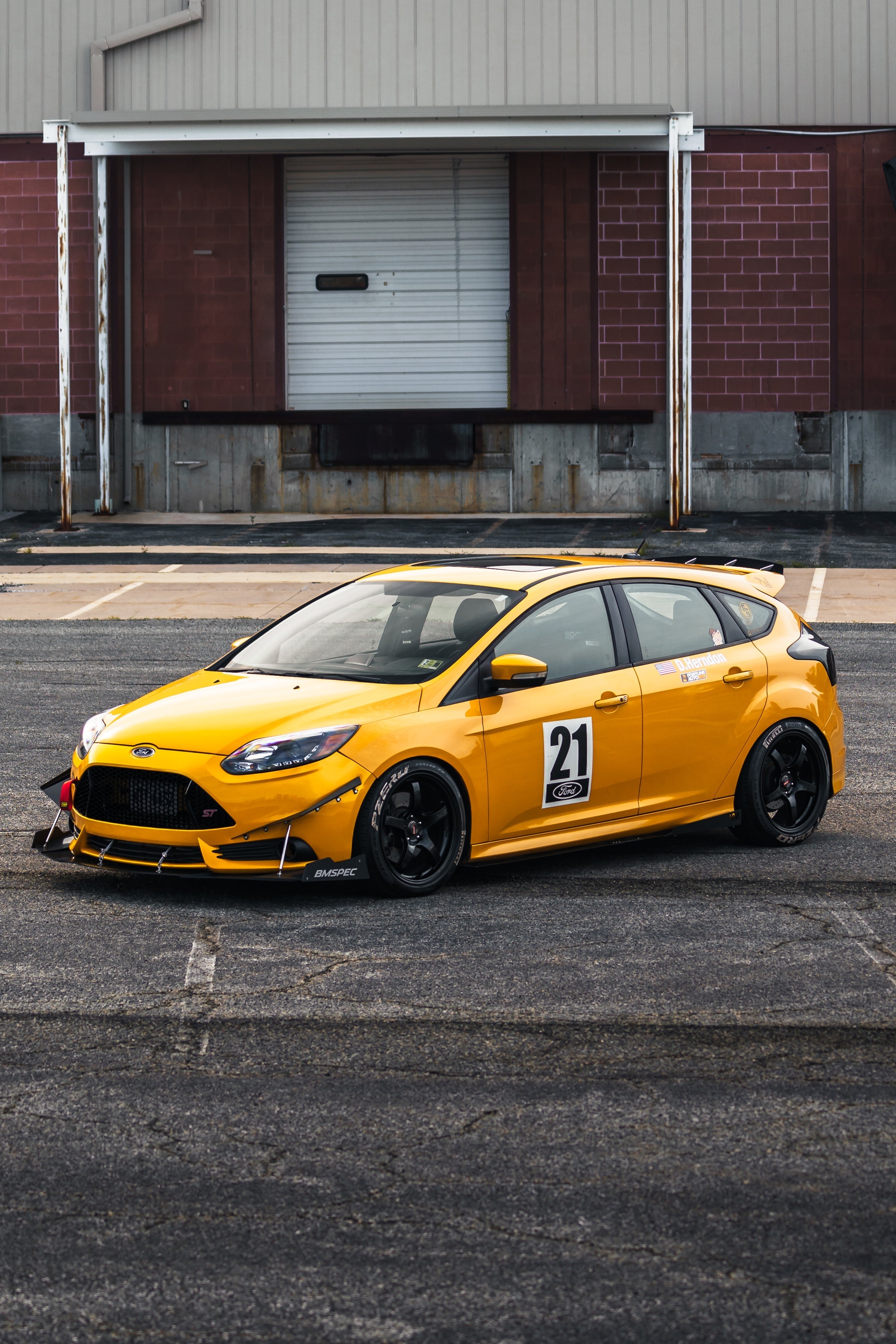 Front three-quarter view of a yellow Focus ST motorsport car with front splitter and race number 21