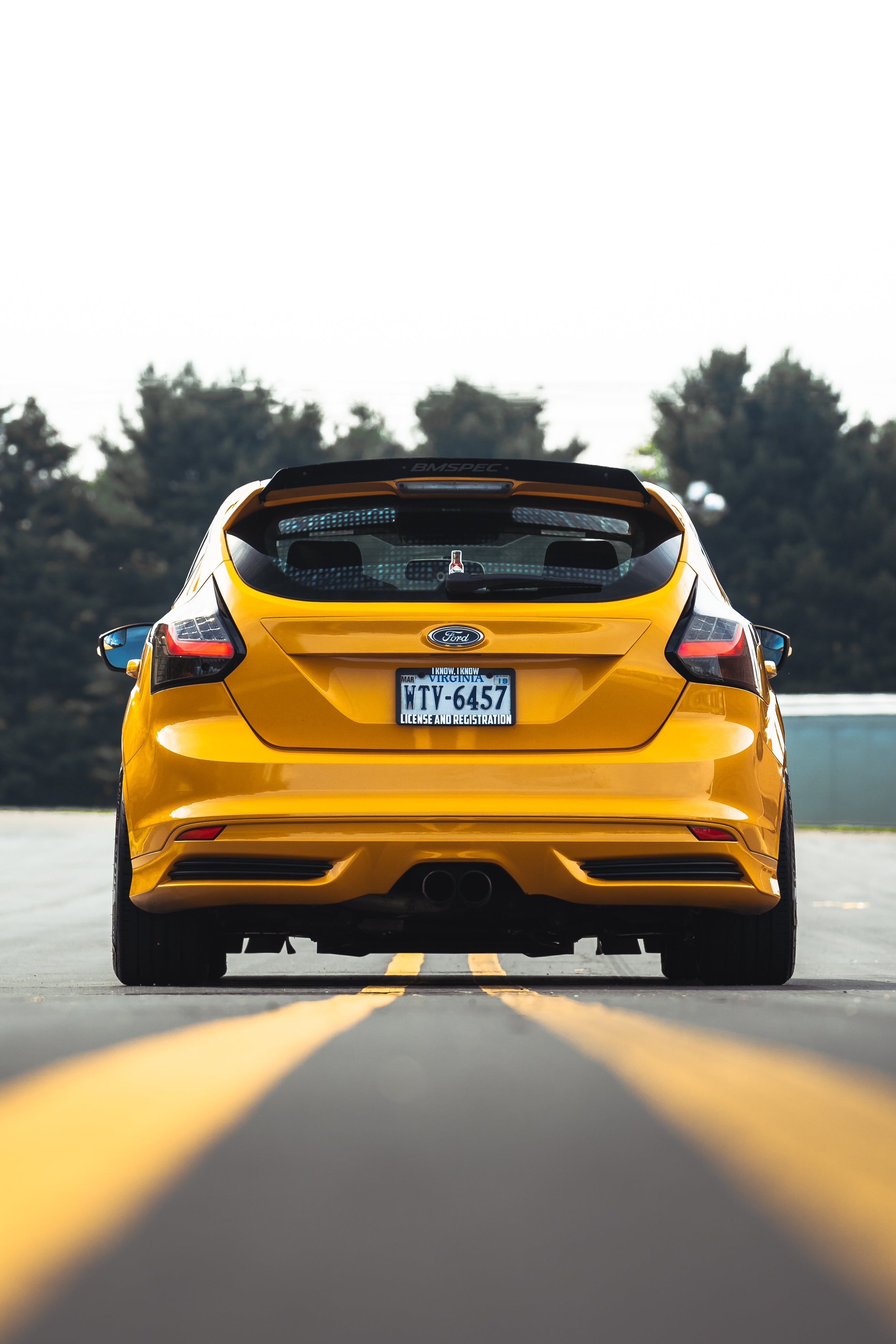 Rear view of a yellow Focus ST with spoiler extension on a track straightaway