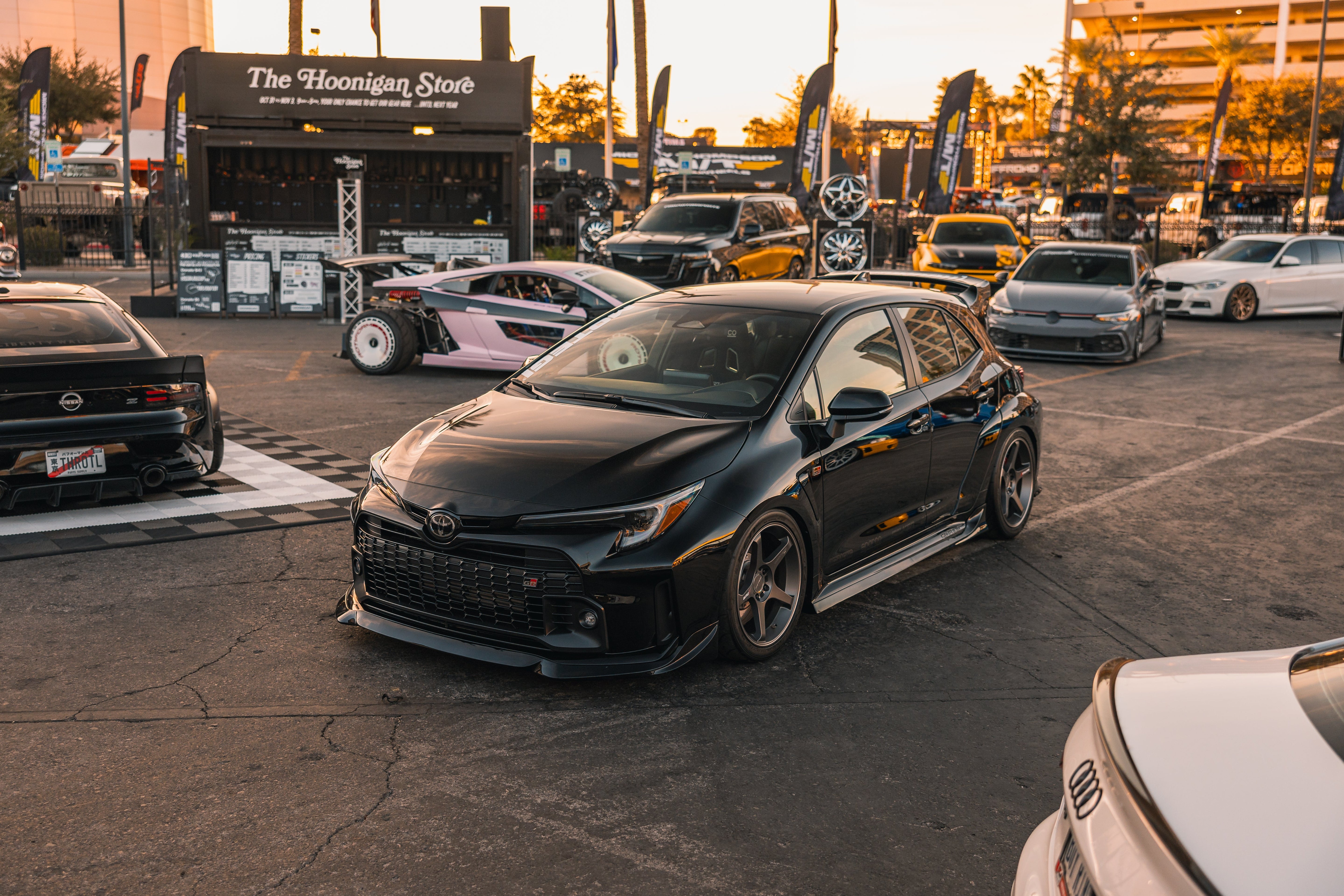 Front three-quarter view of a black GR Corolla with side skirts at a car show