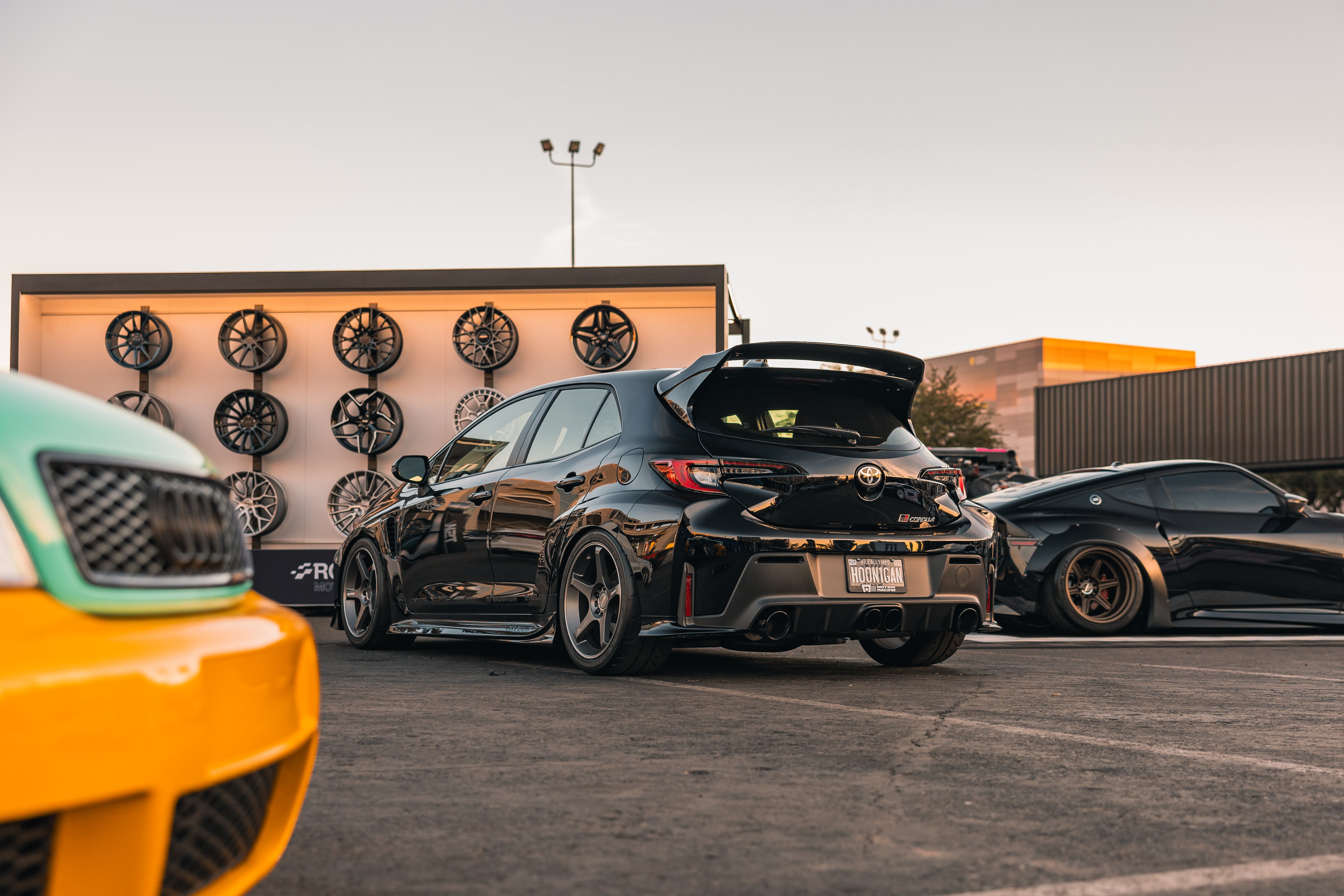 Black GR Corolla with rear spats parked next to other cars at a wheel shop