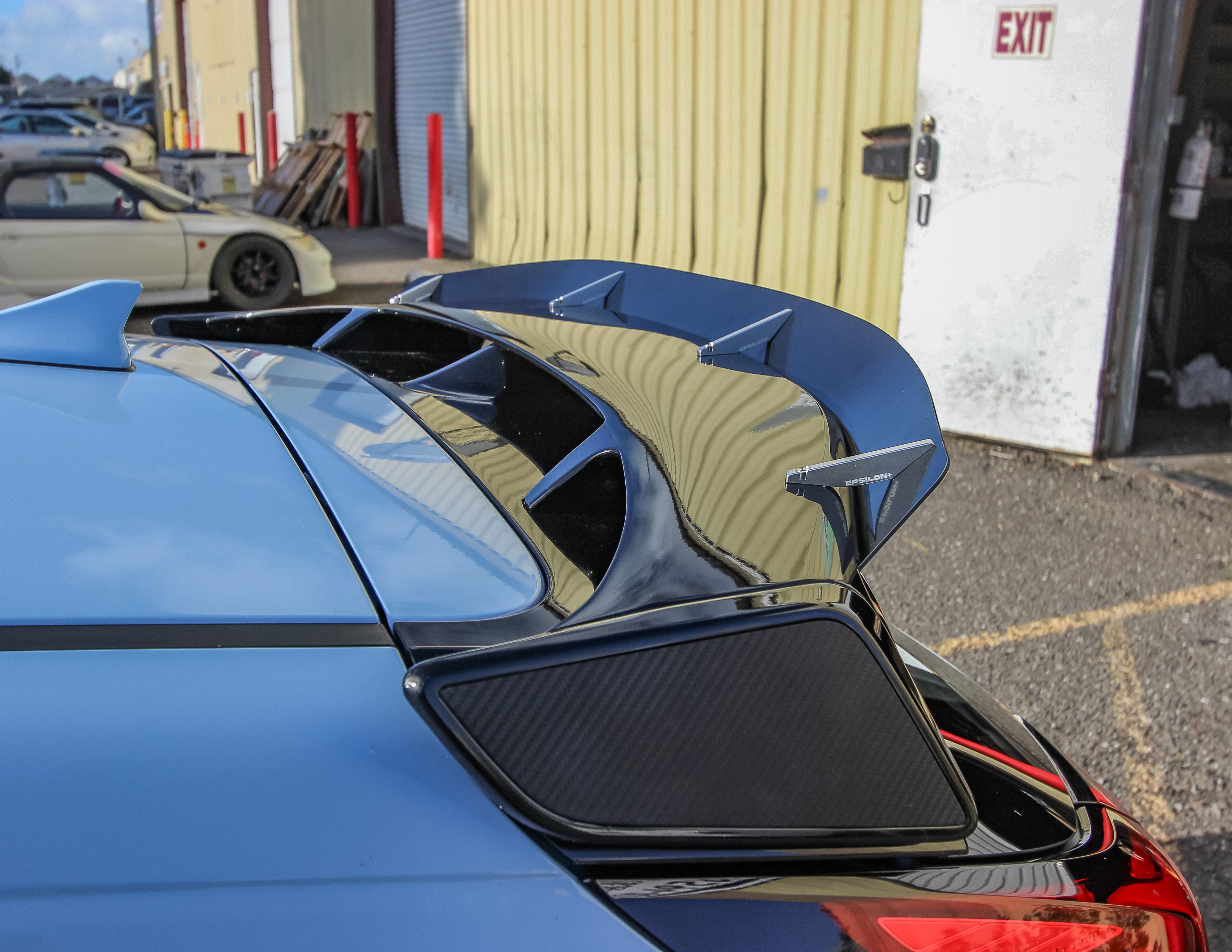 Rear three-quarter view of a blue Veloster N JS with spoiler extension in a parking lot
