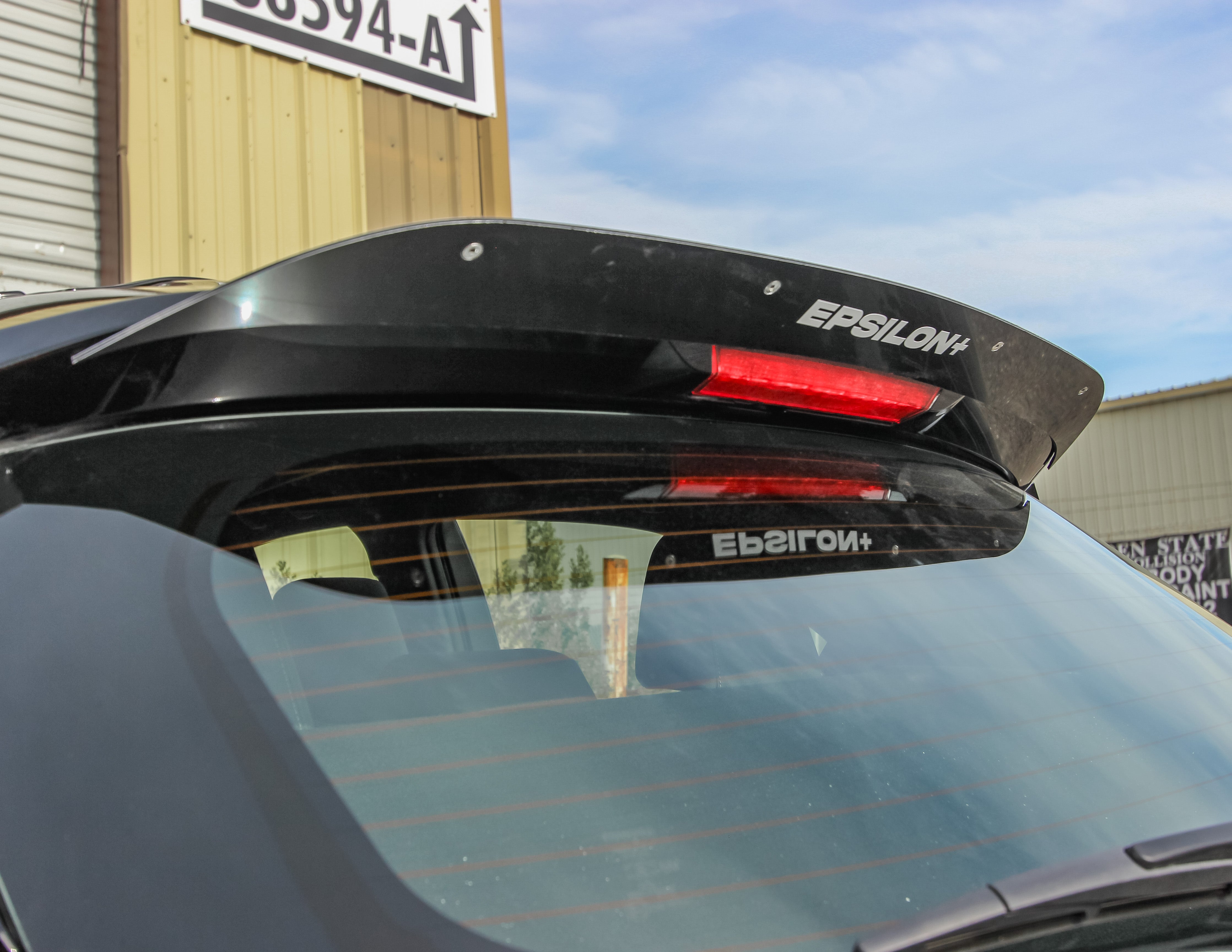 Close-up of the spoiler extension on a black GR Corolla wing with Epsilon+ branding