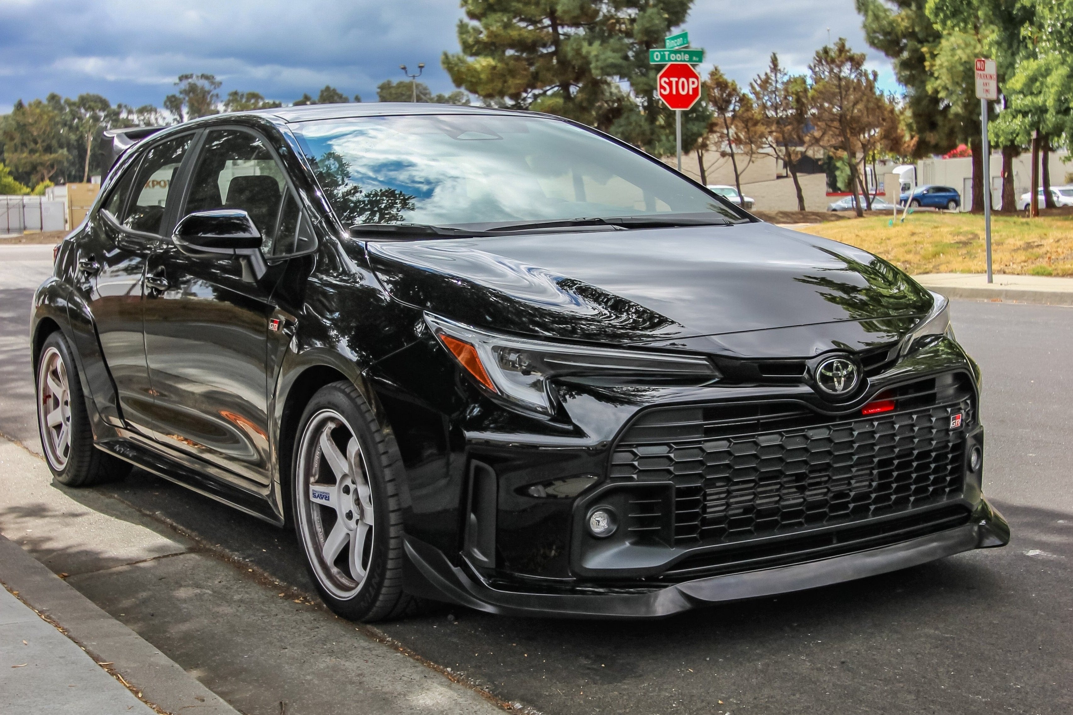 Close-up front view of a red GR Corolla with front lip, hood scoop visible