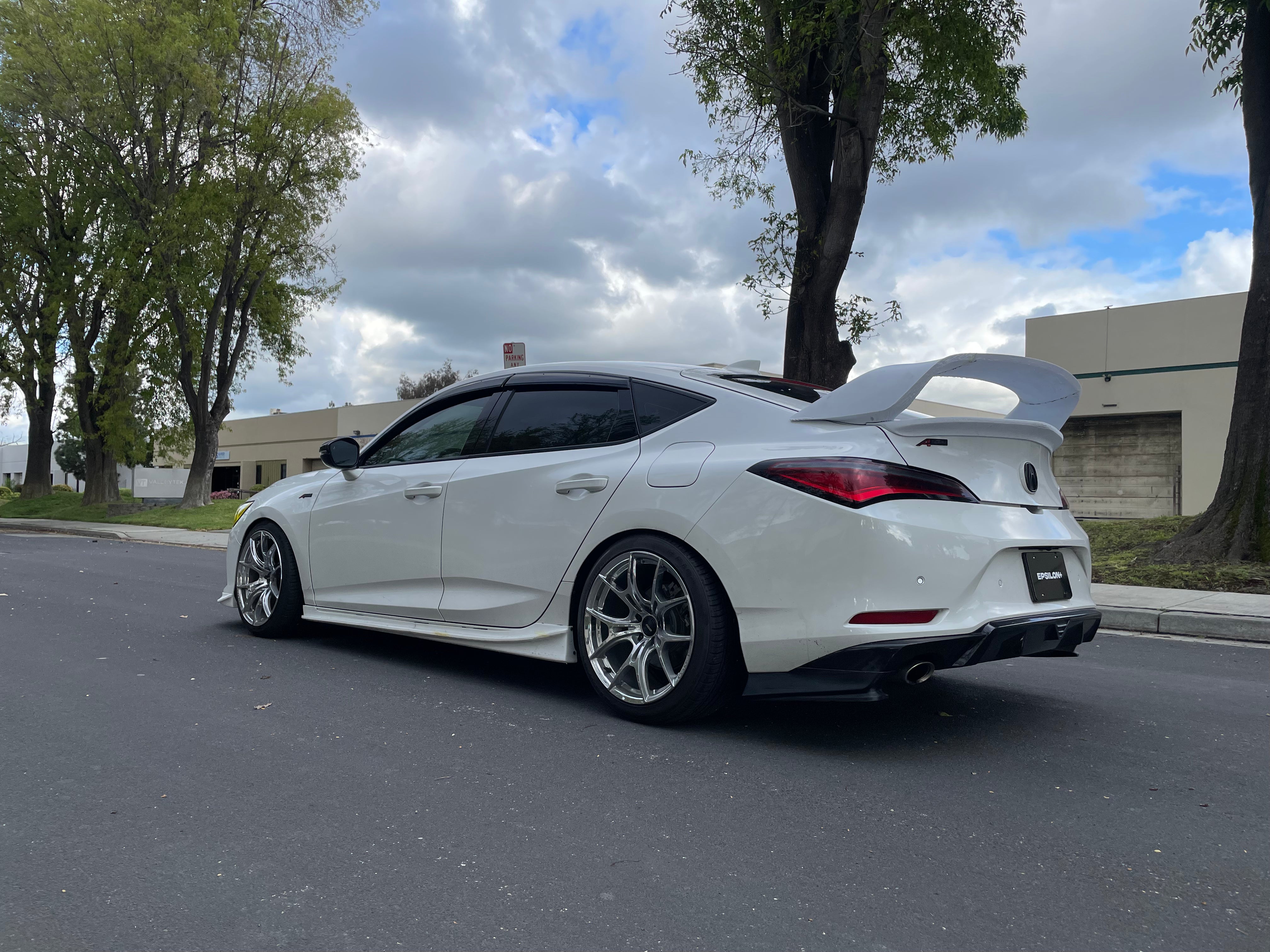Rear three-quarter view of a white Acura Integra with side skirts