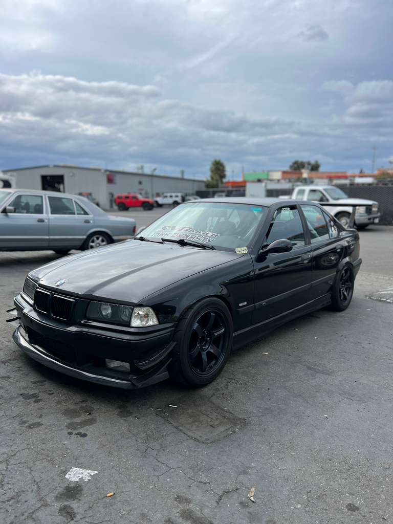 Black BMW E36 M3 with GT wing parked in a parking lot