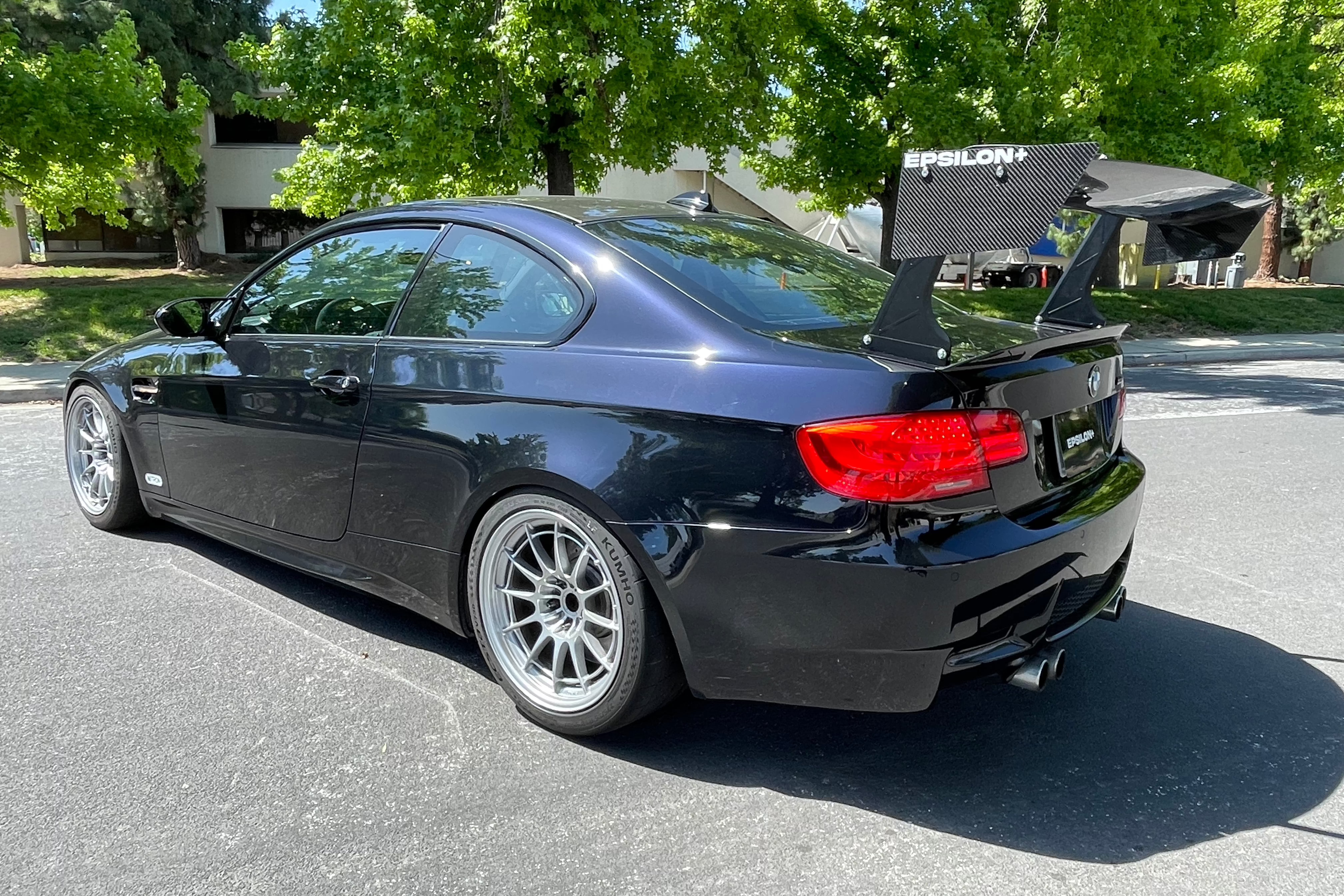 Side-rear view of a black BMW E92 M3 with GT wing and white wheels