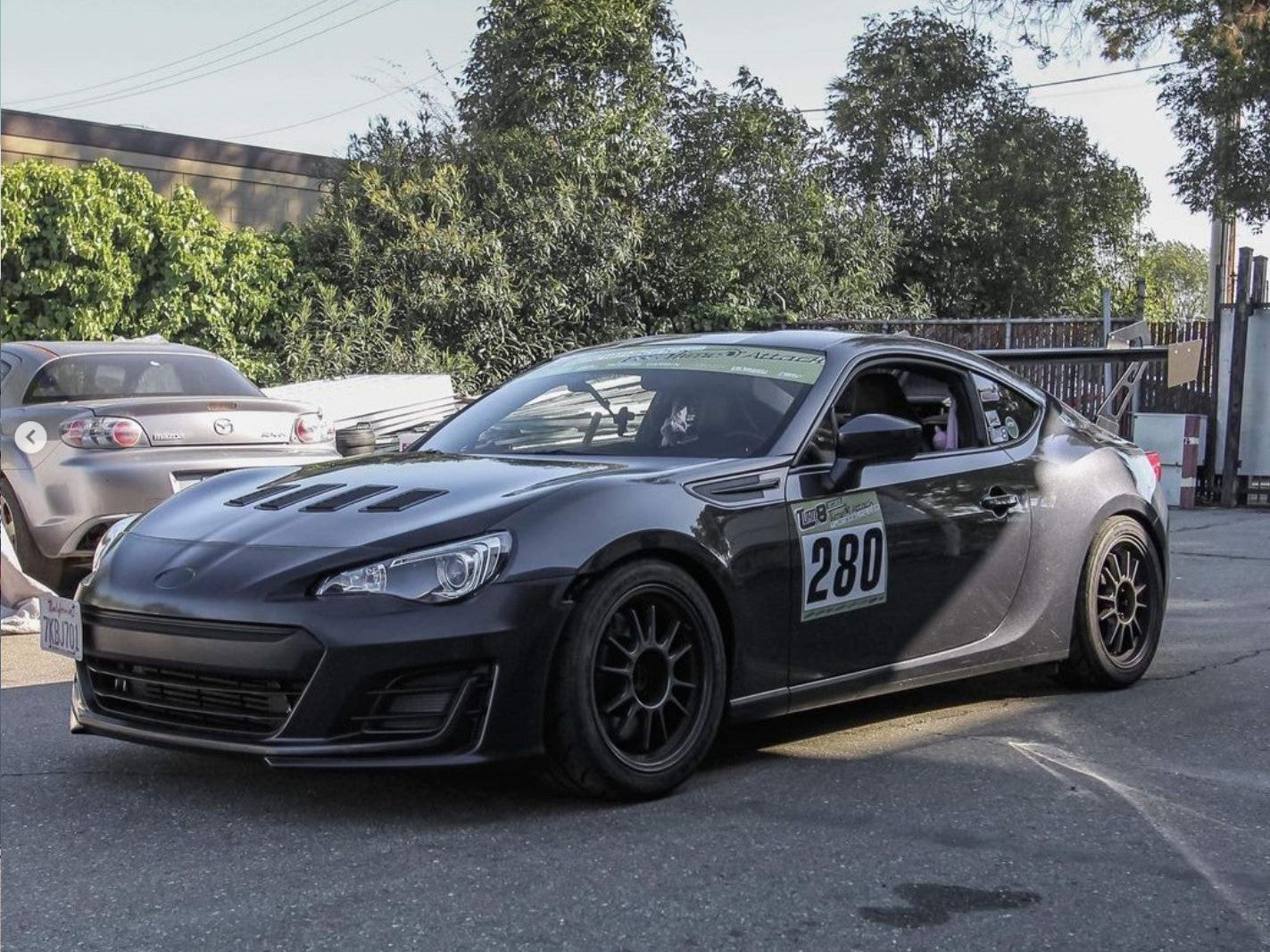 Front three-quarter view of a black BRZ motorsport car with GT wing, race number 280