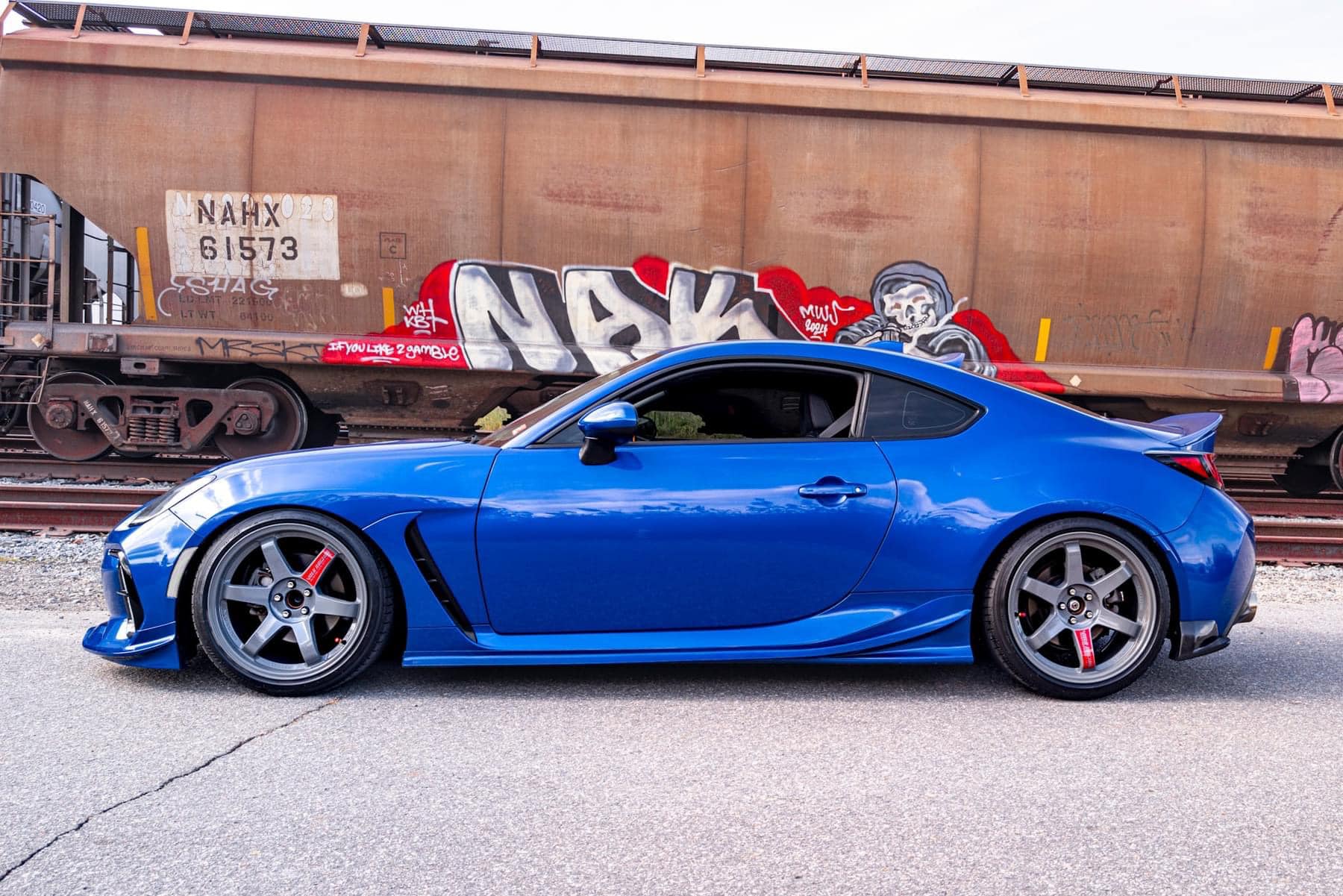 Blue Subaru BRZ ZN8 with side skirts parked beside a railcar