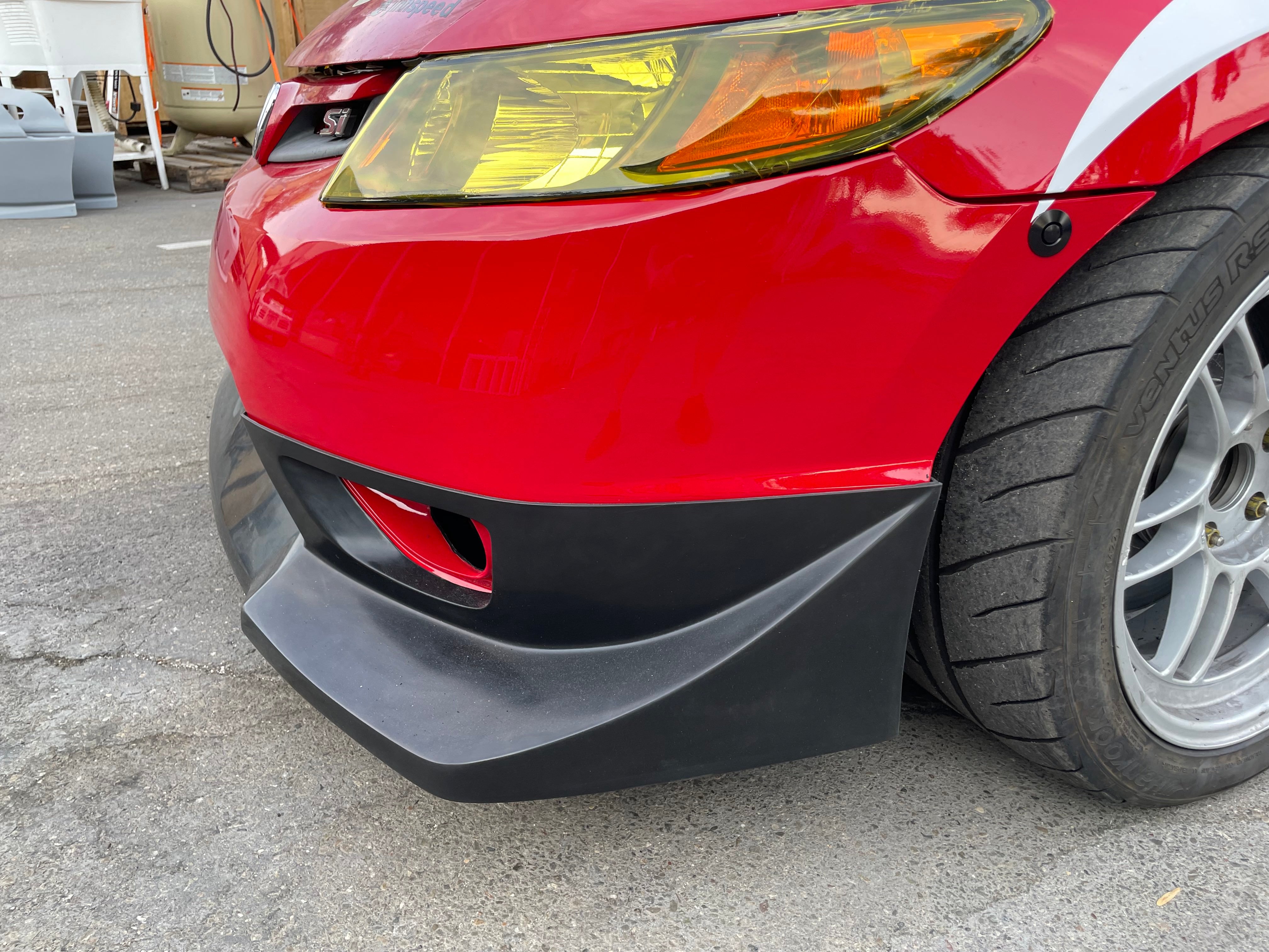 Detail of the front lip corner and yellow headlight on a red Civic Coupe FG2