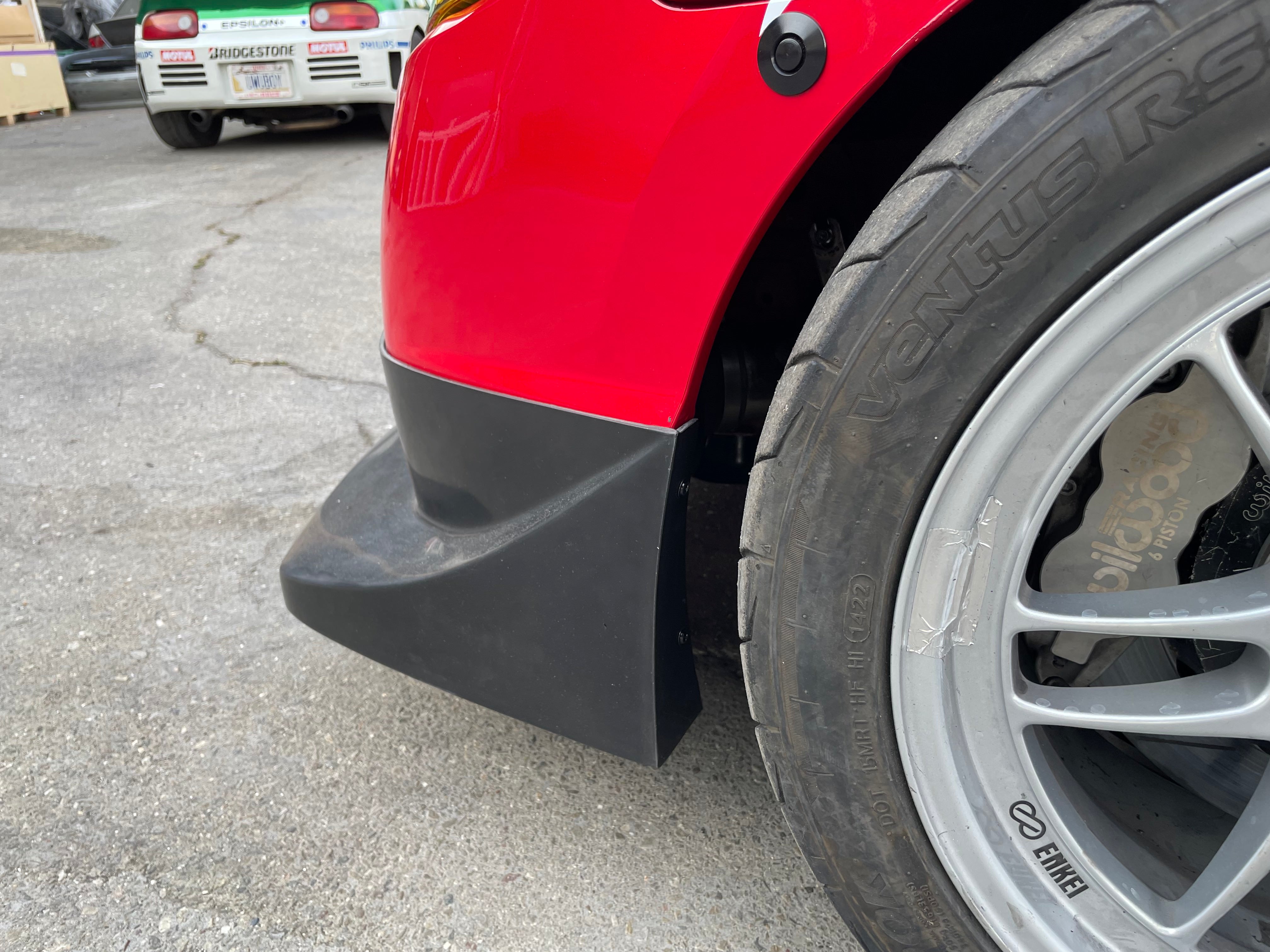 Close-up of the front lip corner beside the wheel on a red Civic Coupe FG2