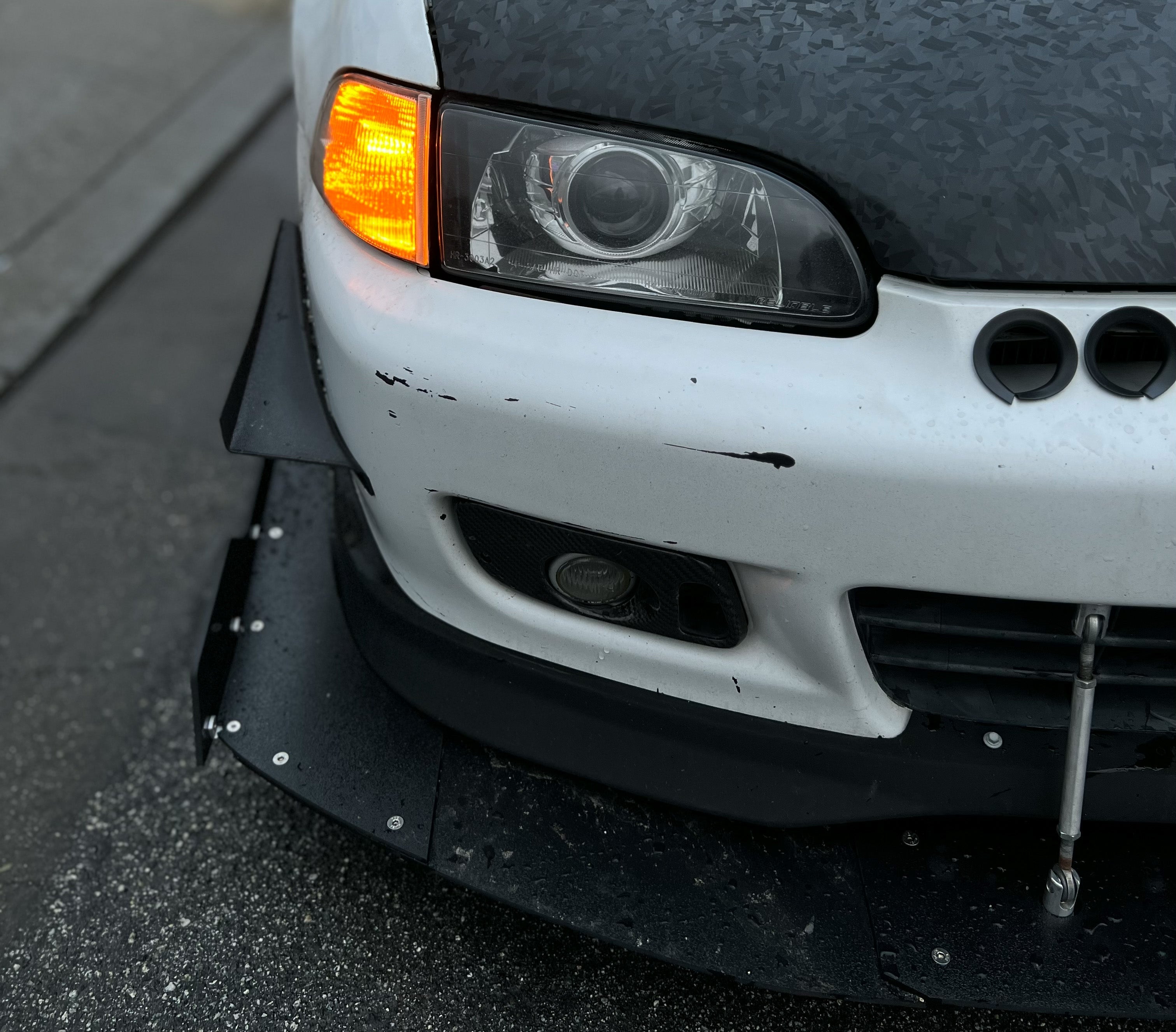 Close-up of the front splitter and headlight on a white Civic EG