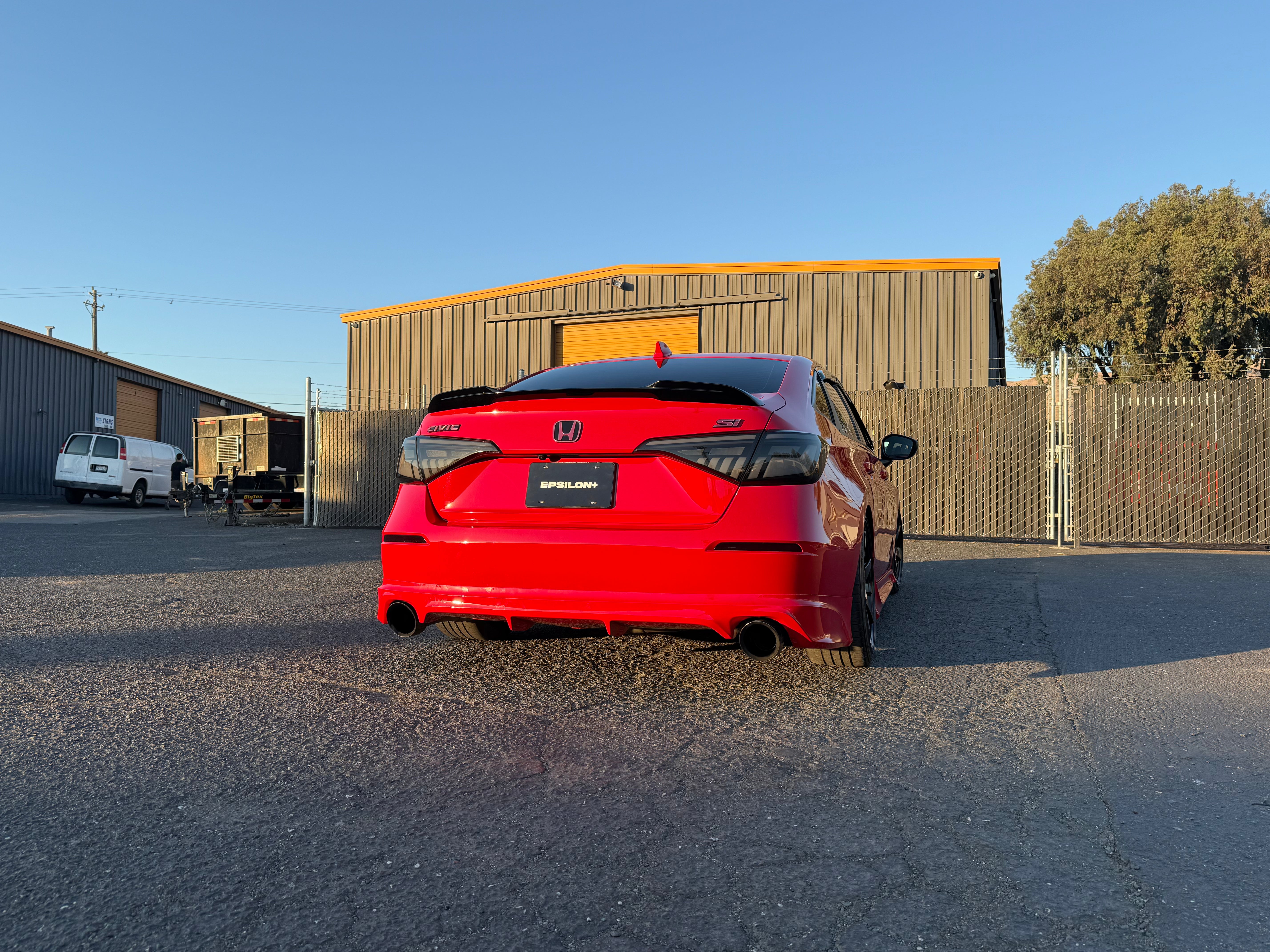 Red Honda Civic Sedan with rear lip beside a warehouse
