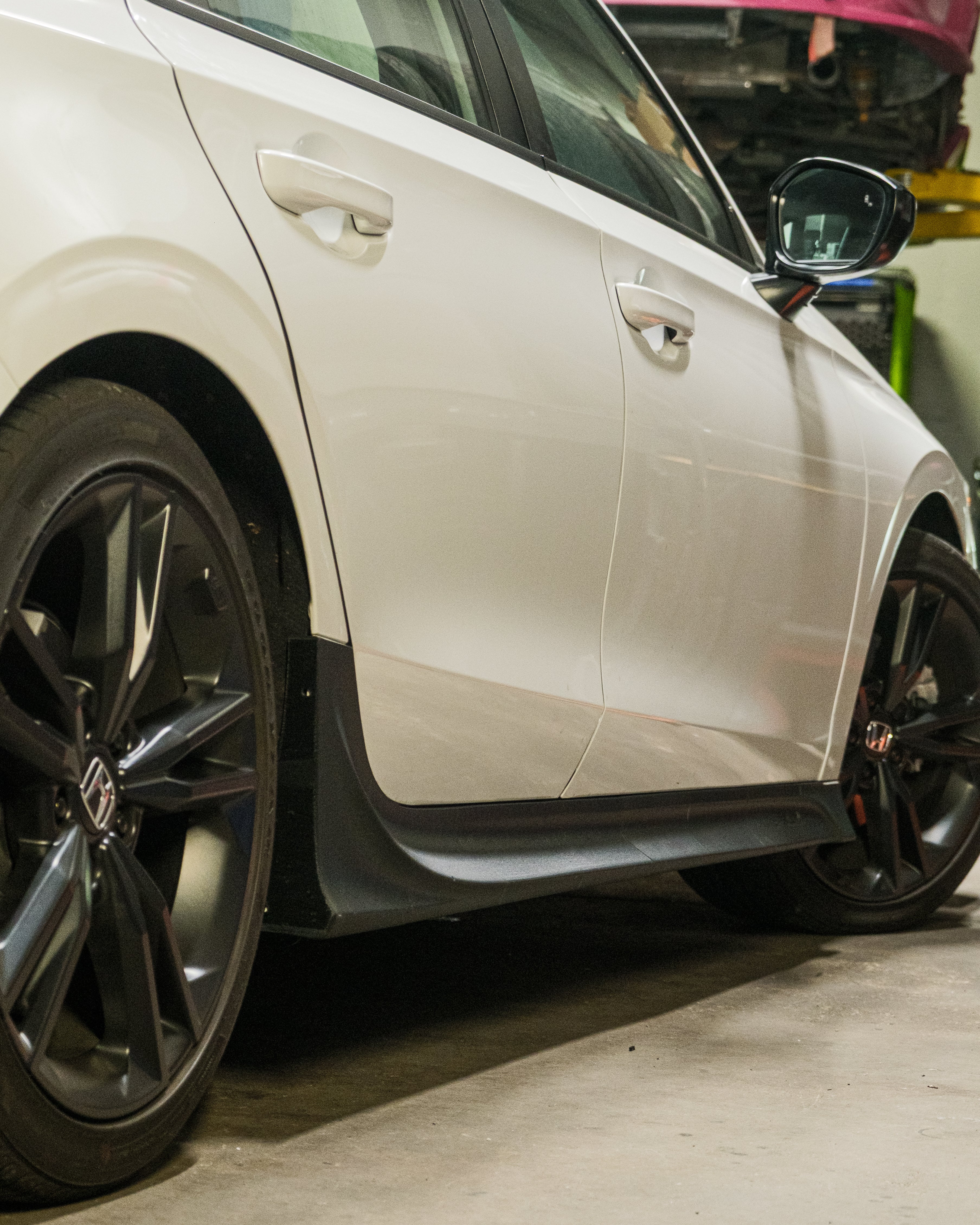 Close-up of the side skirt beside the wheel on a white Honda Civic