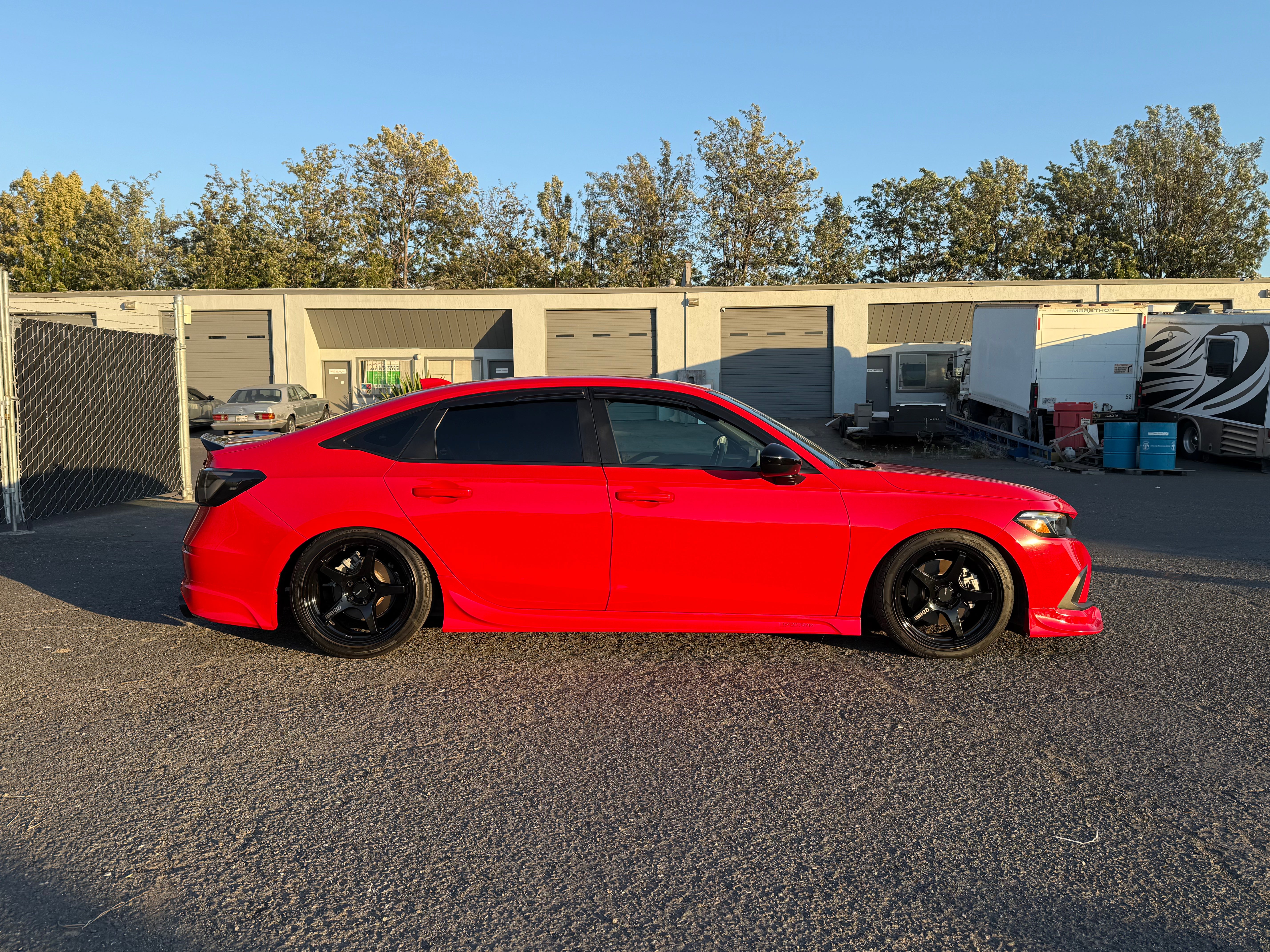 Red Honda Civic with side skirts parked beside industrial units