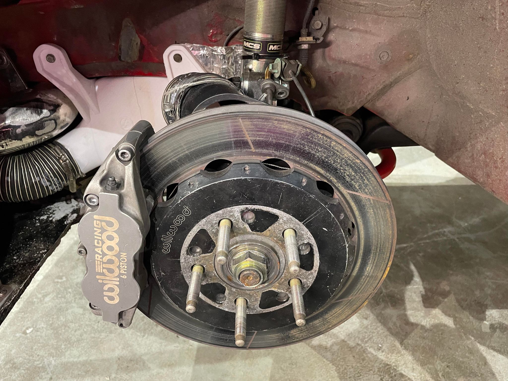 Brake rotor duct installed at the caliper on a red Civic Coupe race car