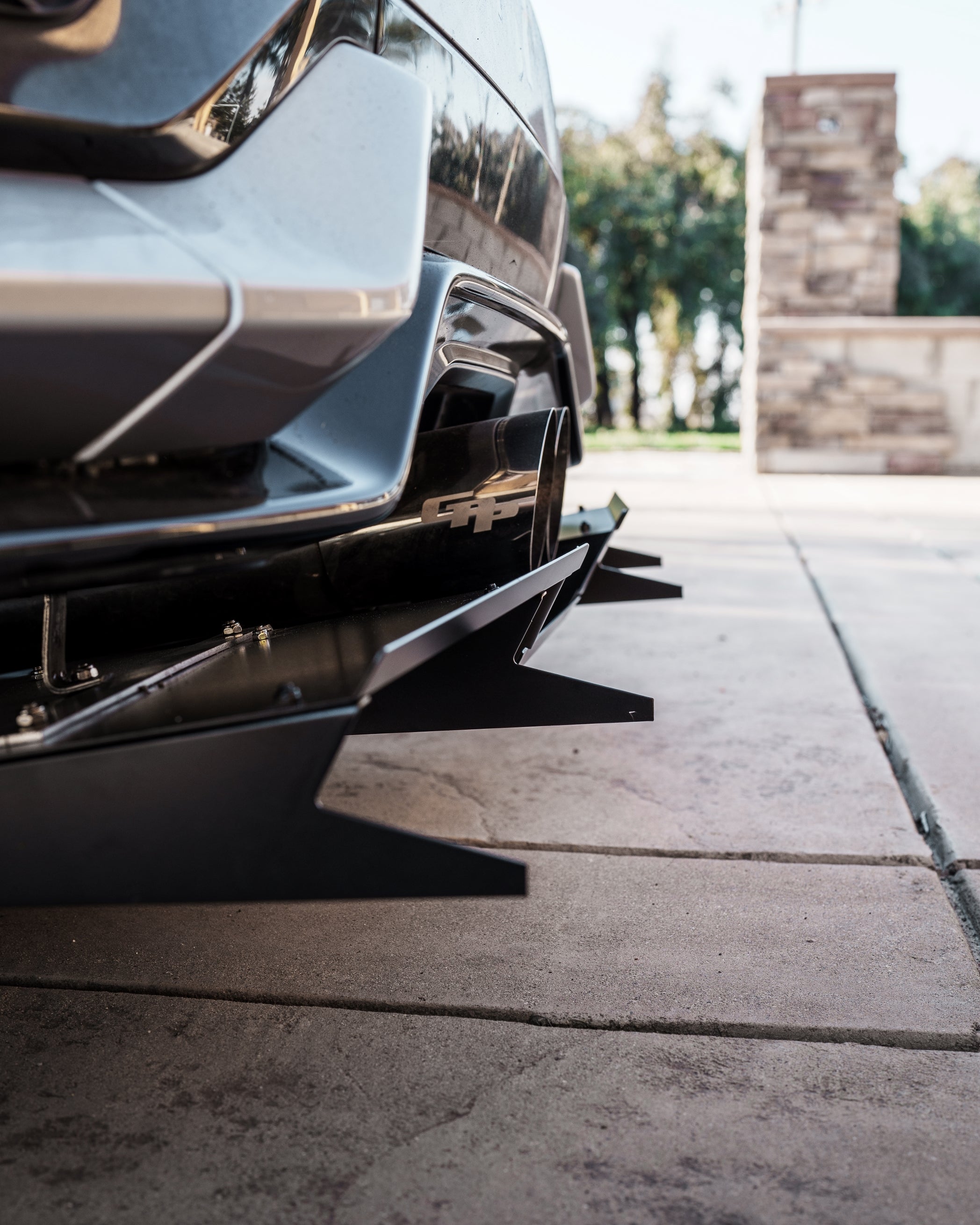 Low-angle close-up of the V1C+ diffuser mounted under a Civic FK7 rear bumper