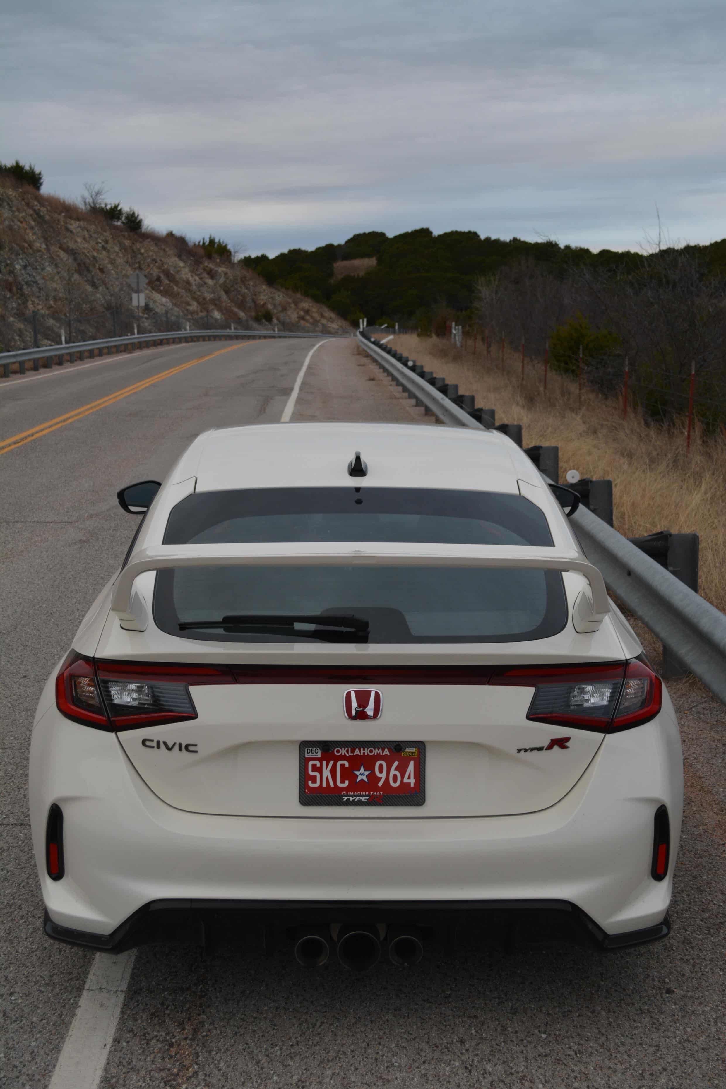 Rear-on view of a white Honda Civic FL5 with Sport Wing on a mountain road