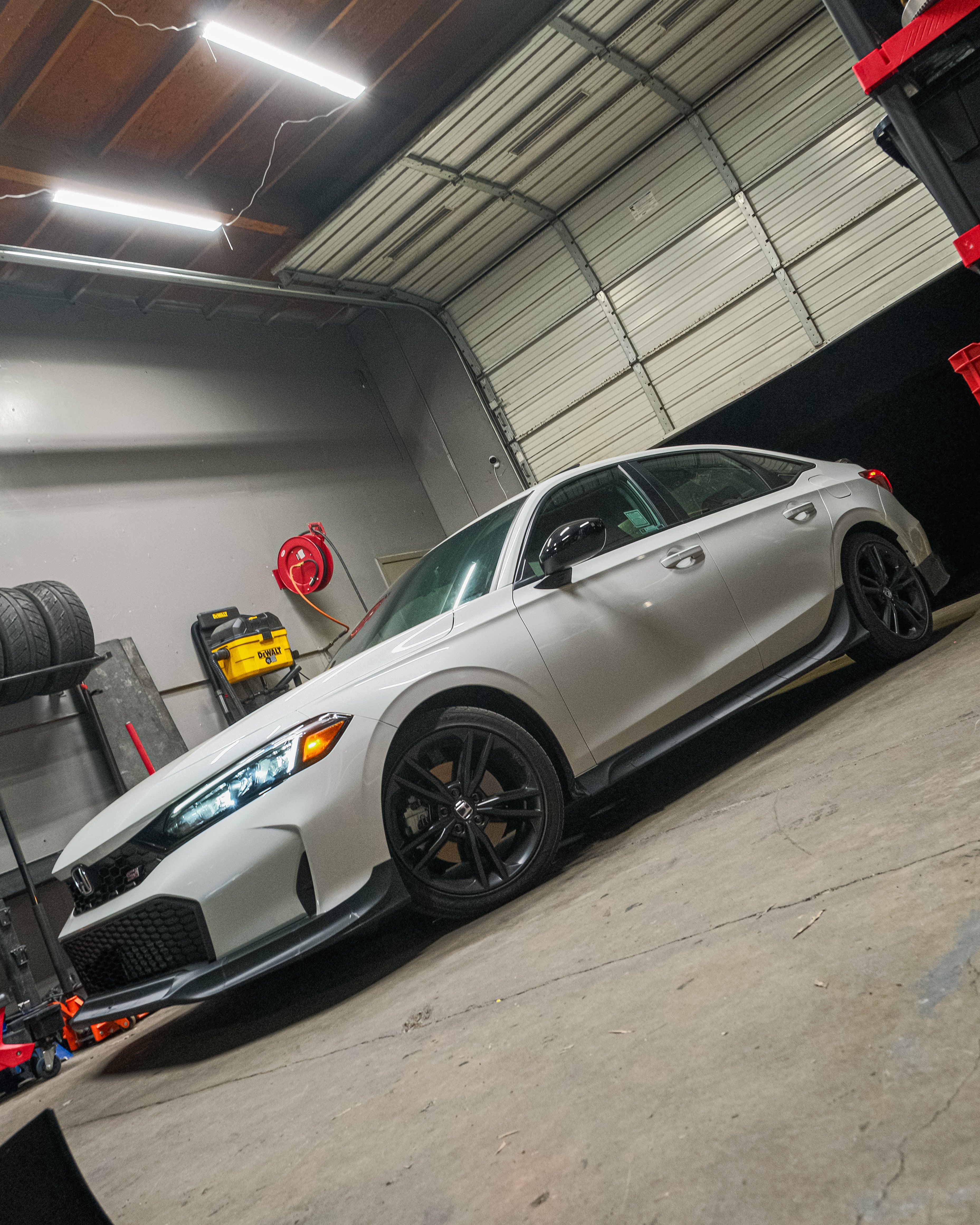 Side profile of a white Honda Civic with the Epsilon+ front lip in the workshop